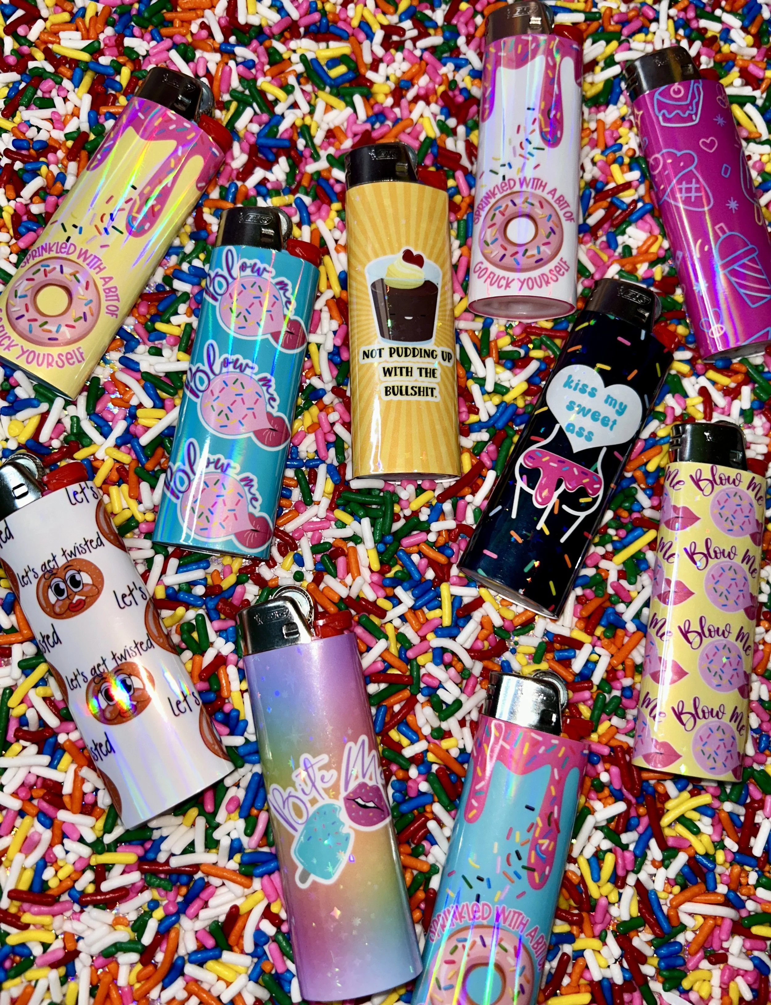 Colorful lighters with playful designs and phrases scattered on a bed of rainbow sprinkles.