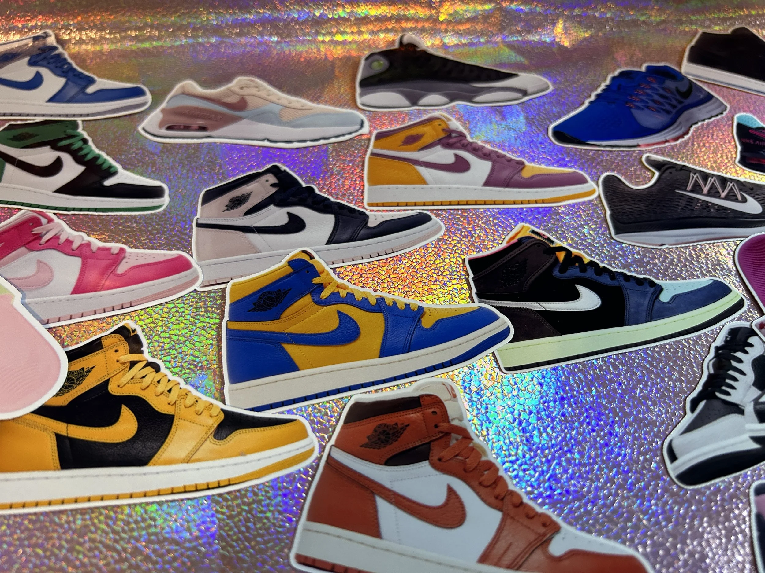 Stickers of various colorful Nike sneakers on a holographic background.