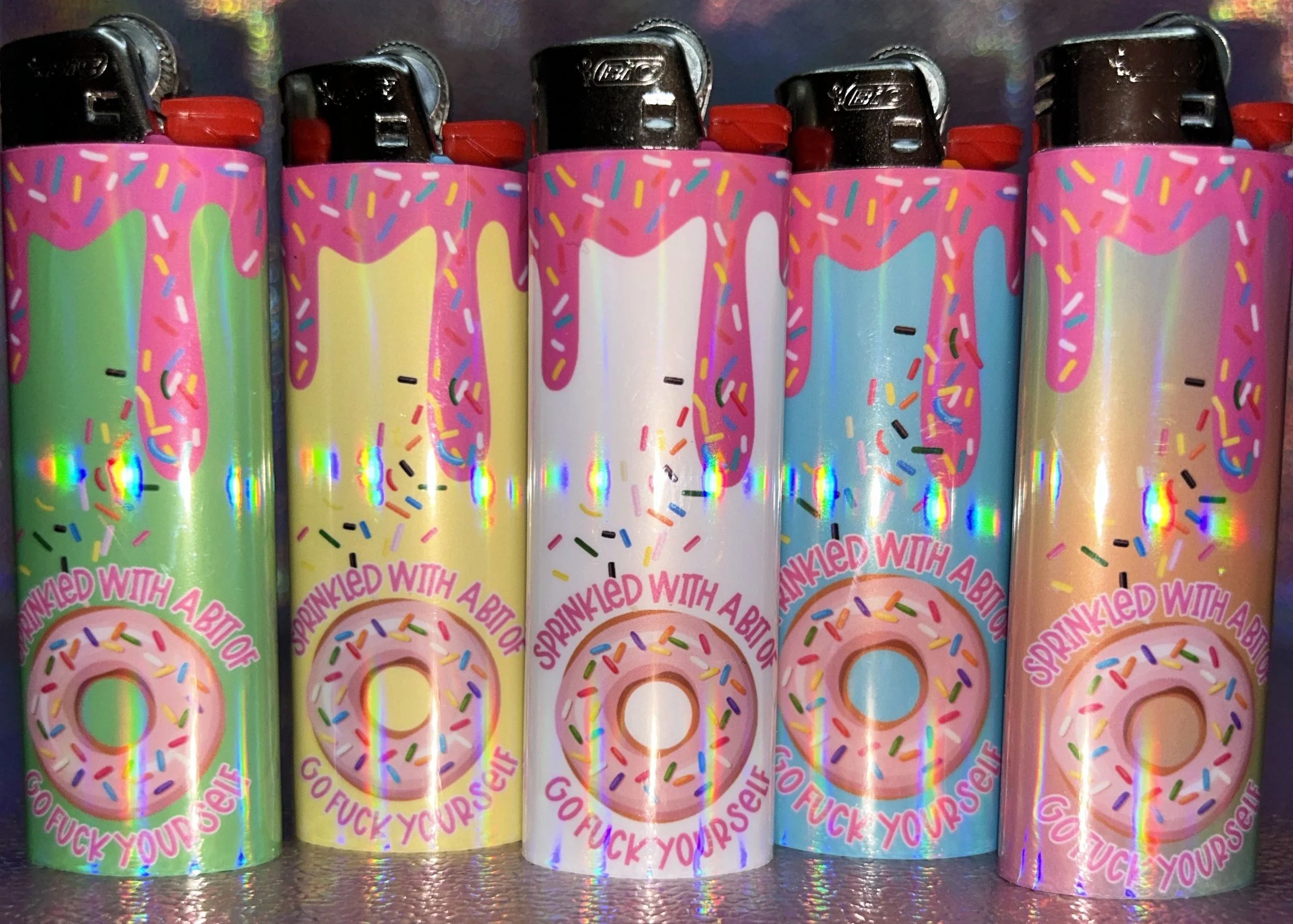 Six colorful lighters with donut and sprinkle designs, featuring the phrase "sprinkled with a bit of go f*** yourself".
