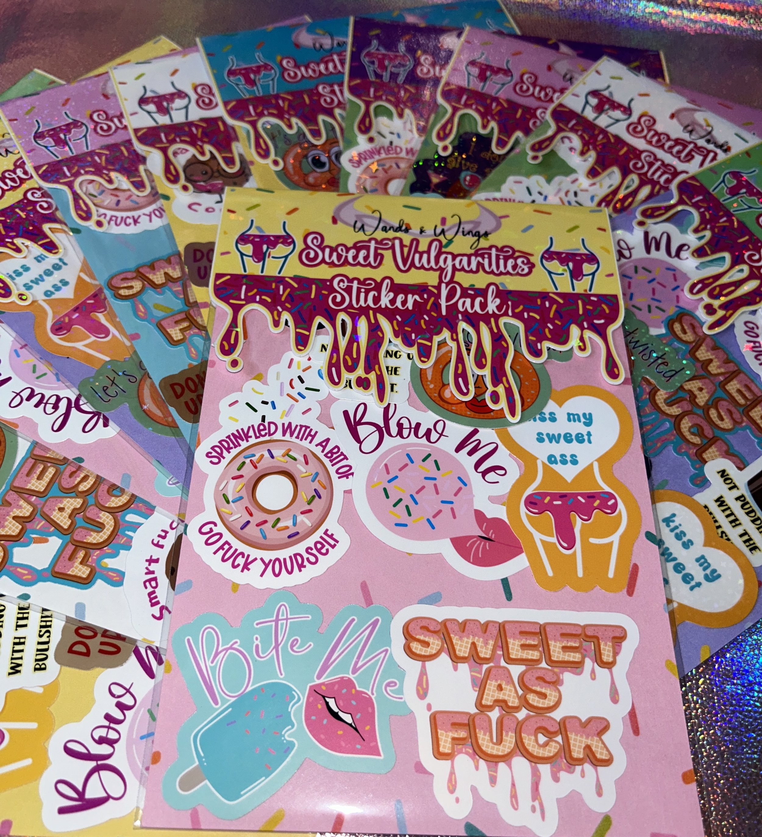 Colorful sticker pack with humorous and irreverent phrases on a glittery background.
