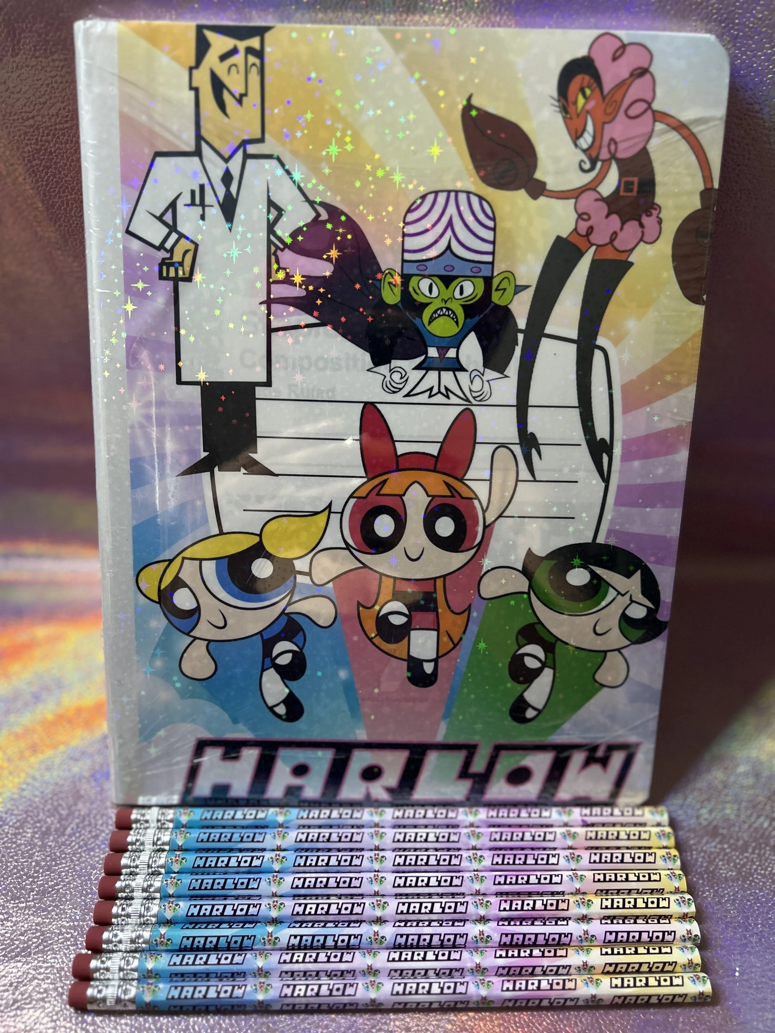 Colorful notebook cover featuring cartoon characters and themed pencils labeled "Harlow."