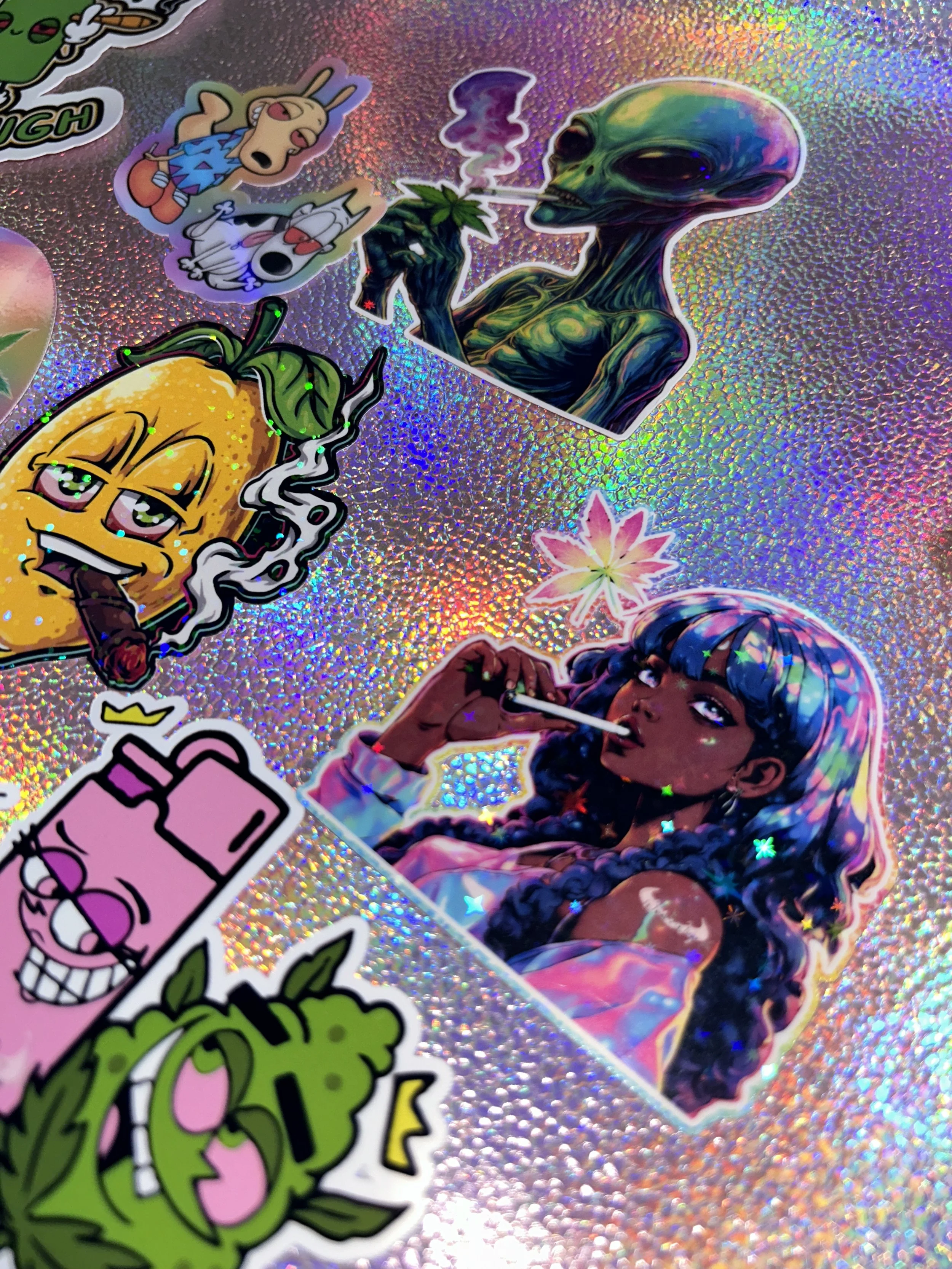 Collection of colorful stickers featuring characters and cartoon imagery on a shiny, iridescent background.