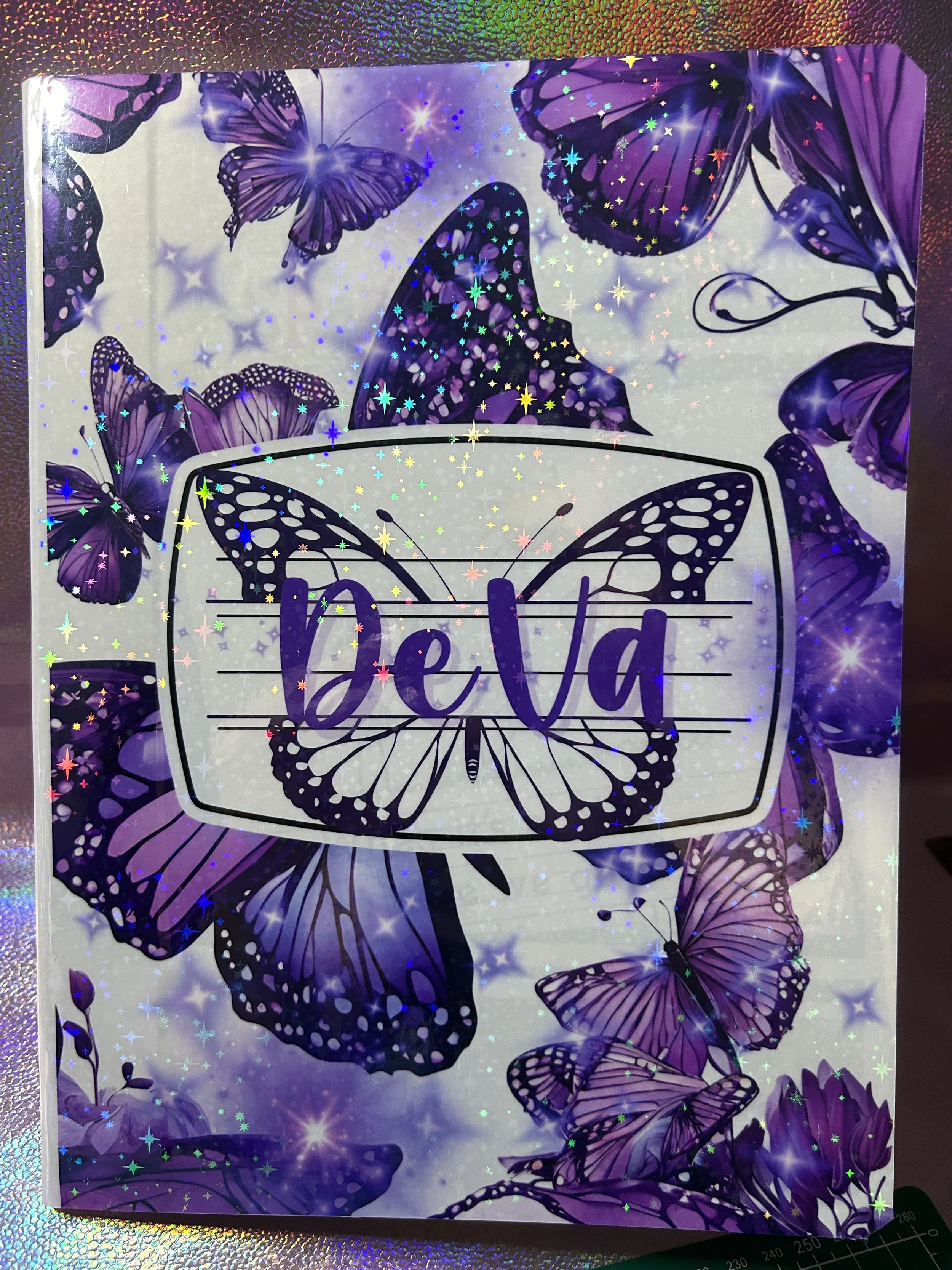 Purple butterfly-themed notebook cover with sparkling stars and the word "DeVa" in stylized text.