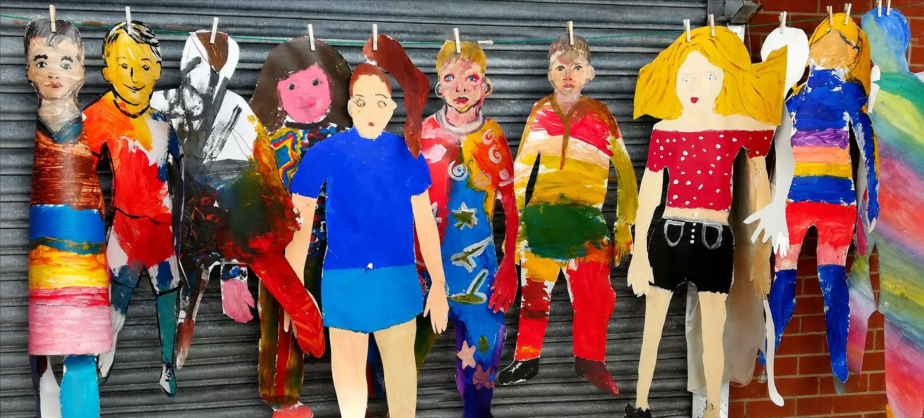 Life-size, colourful self-portraits created by children in Maesgeirchen, North Wales, hang on a washing line as part of a community art project
