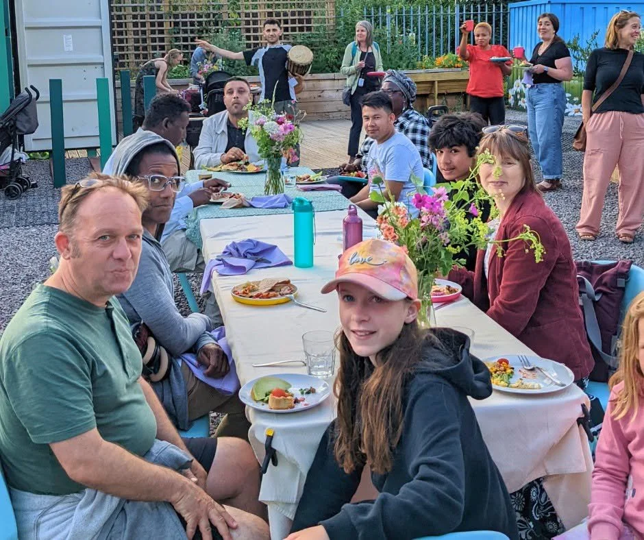 People enjoying an outdoor community summer supper at Railway Gardens, run by Green Squirrel, one of the organisations supported through the Community Anchor Development Programme.
