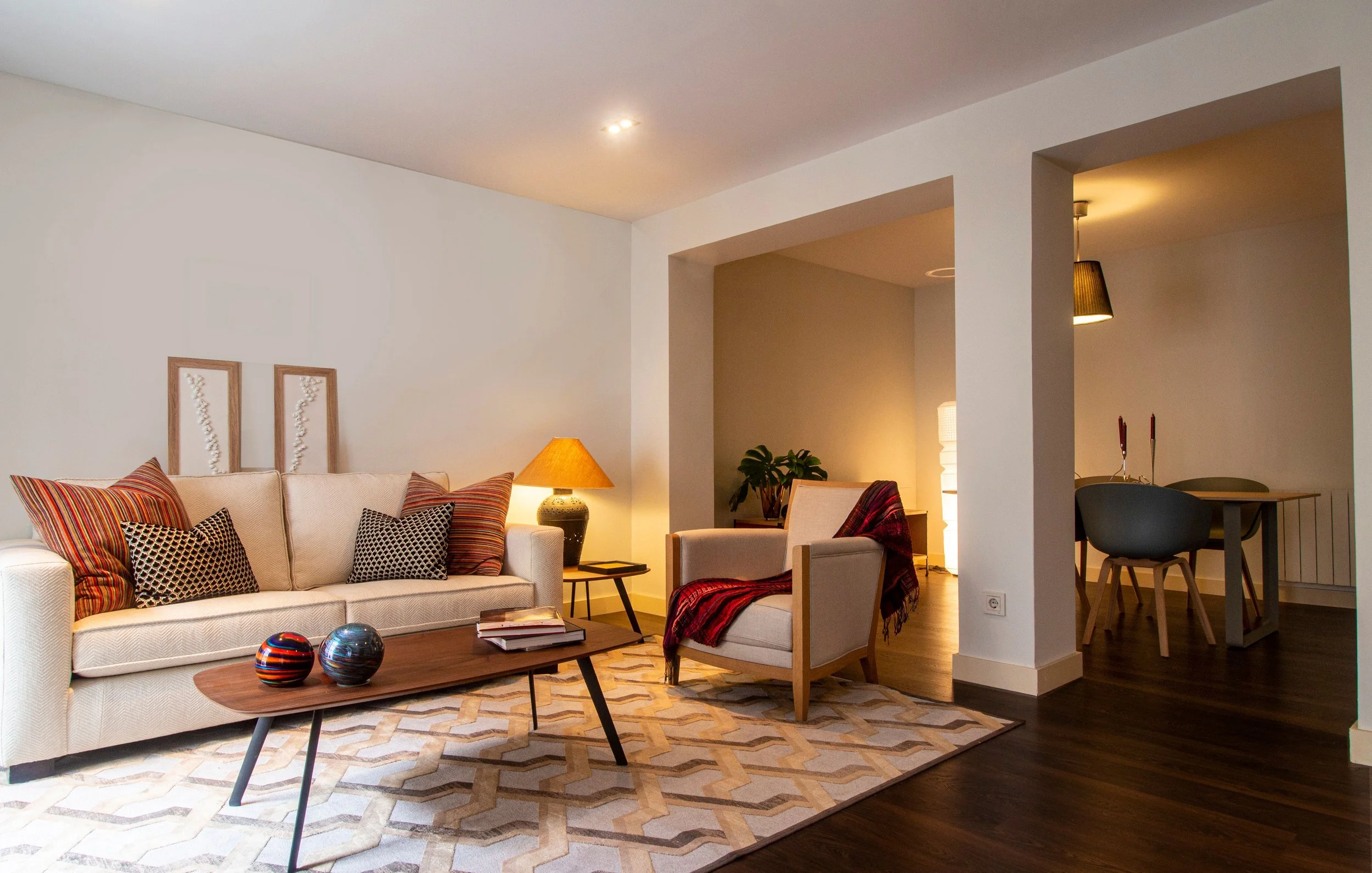 Contemporary living room with neutral seating, warm lighting and an open-plan dining area
