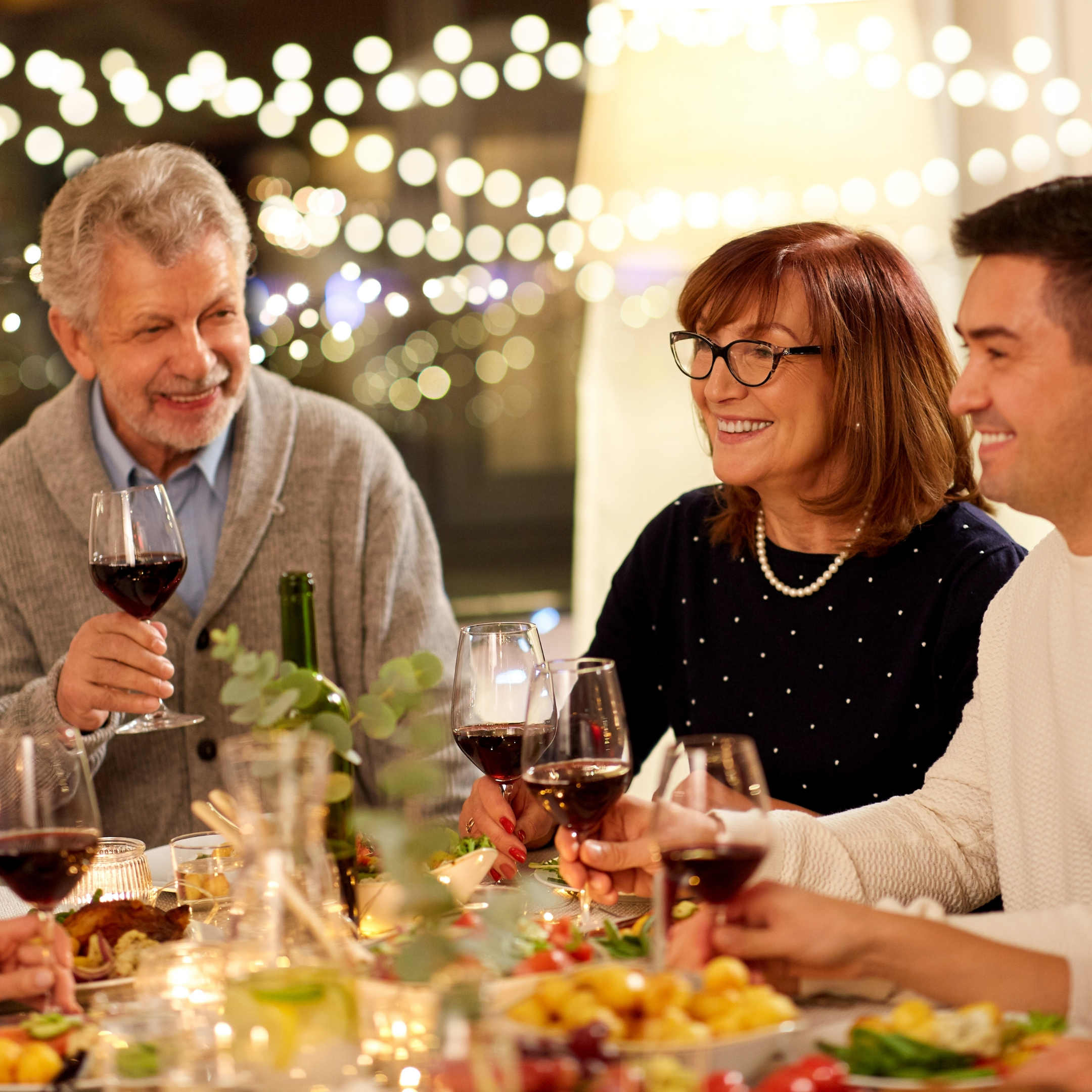 Family and friends gathered around a dining table enjoying a relaxed meal and conversation together.