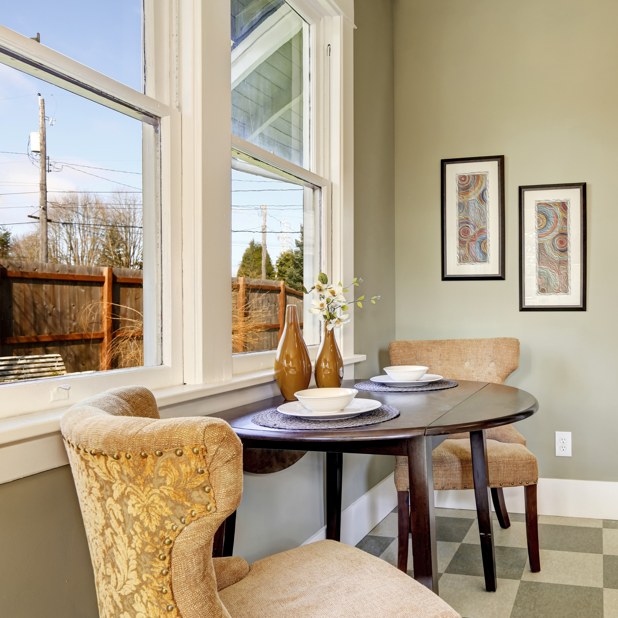 Space-saving drop-leaf dining table positioned beside a window with two upholstered dining chairs.