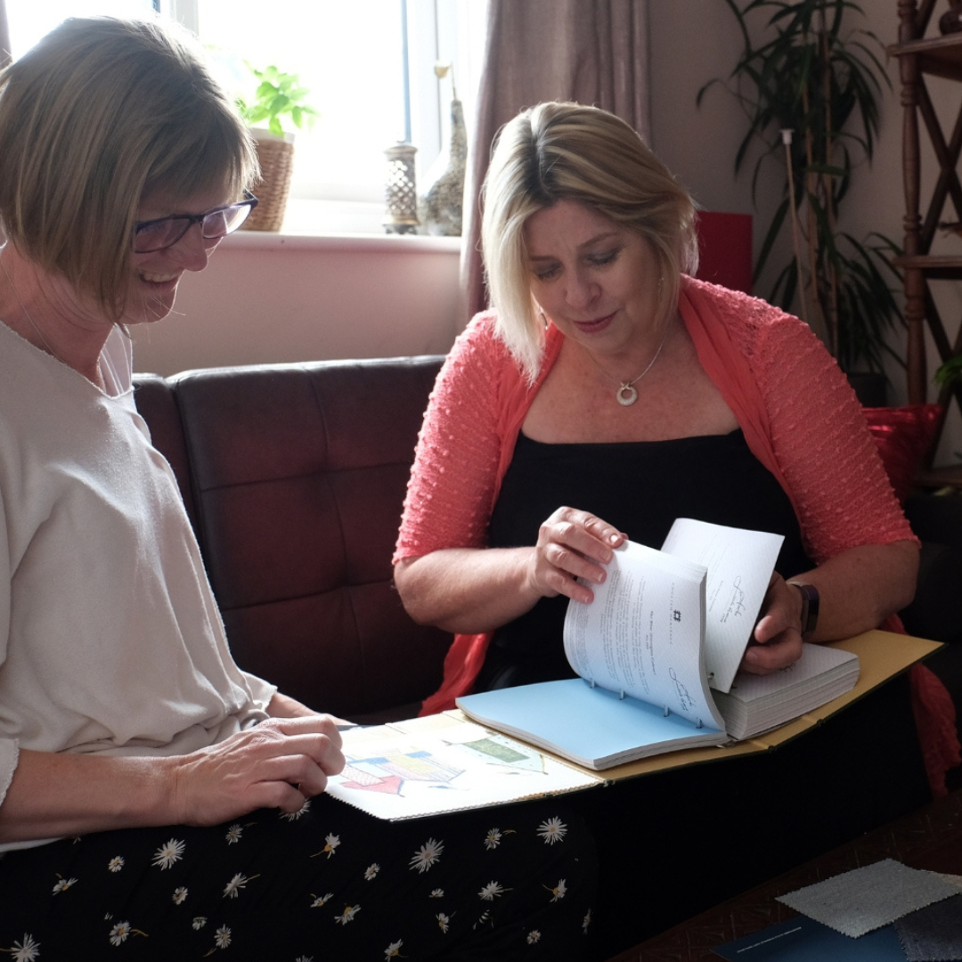 Interior designer discussing plans and colour samples with a client during a home consultation.