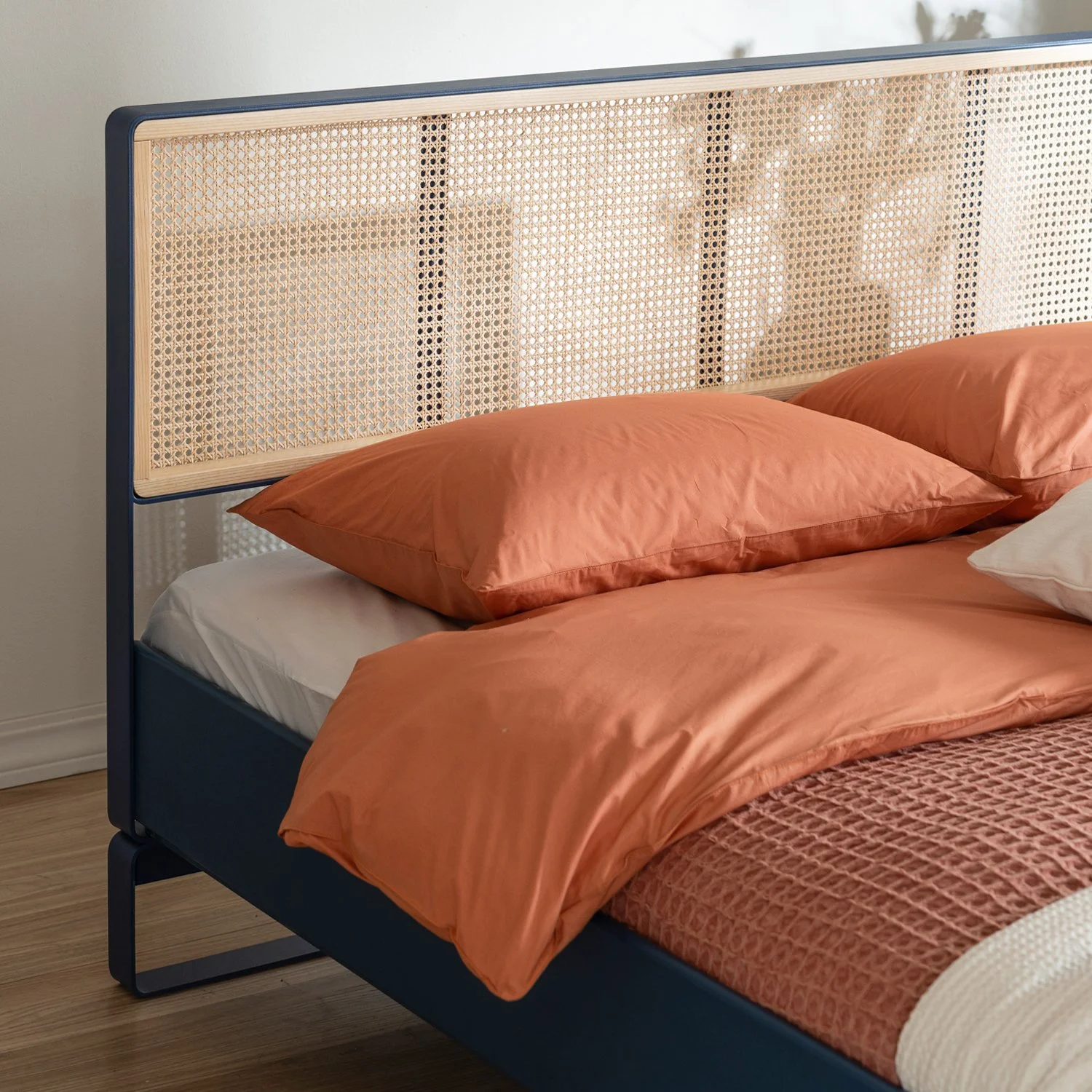 Close up of the Minimal bed frame, showing the intersection of lacquered wood and metal supports.