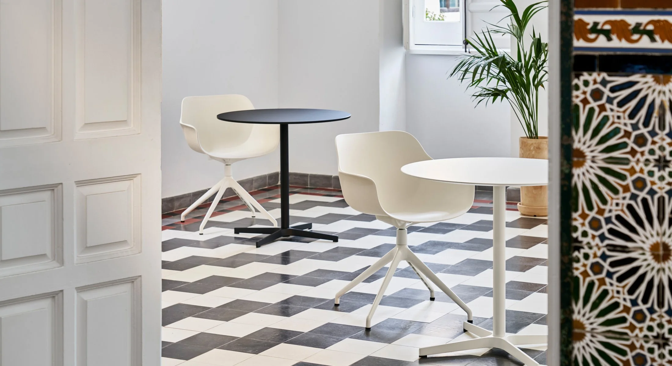 Vista cenital de la mesa Bistro que resalta el diálogo geométrico entre el diseño del mueble y el suelo de baldosa hidráulica.