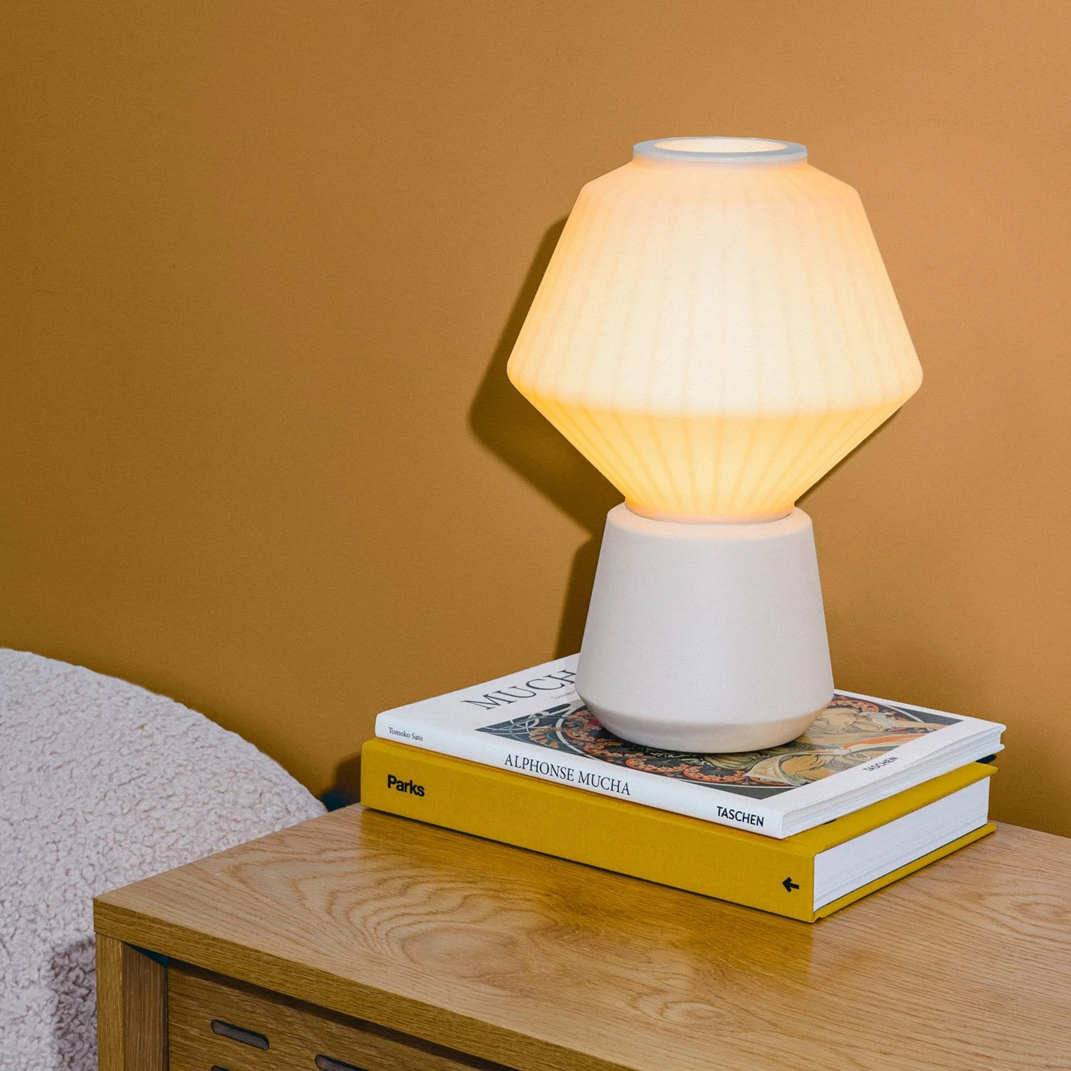 Lámpara de mesa de diseño minimalista aportando una iluminación cálida y serena en un ambiente de dormitorio moderno.