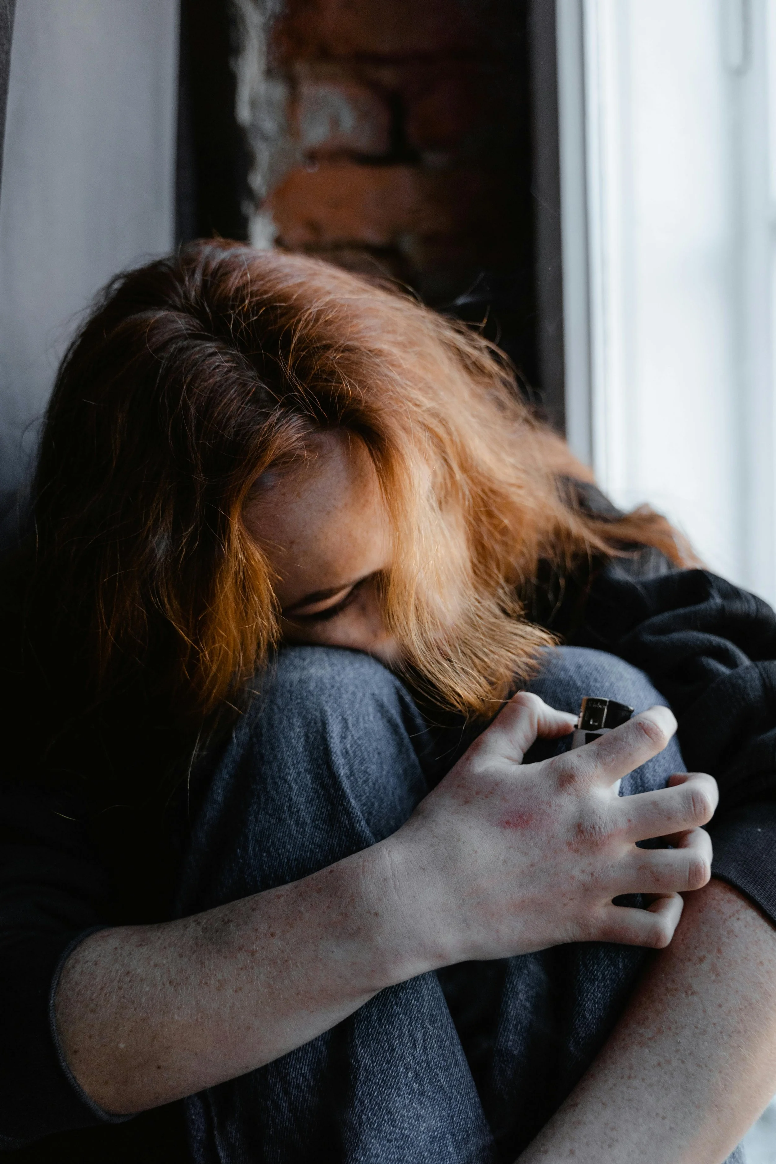 Woman sitting alone in distress, head in hands, reflecting emotional pain related to unresolved trauma