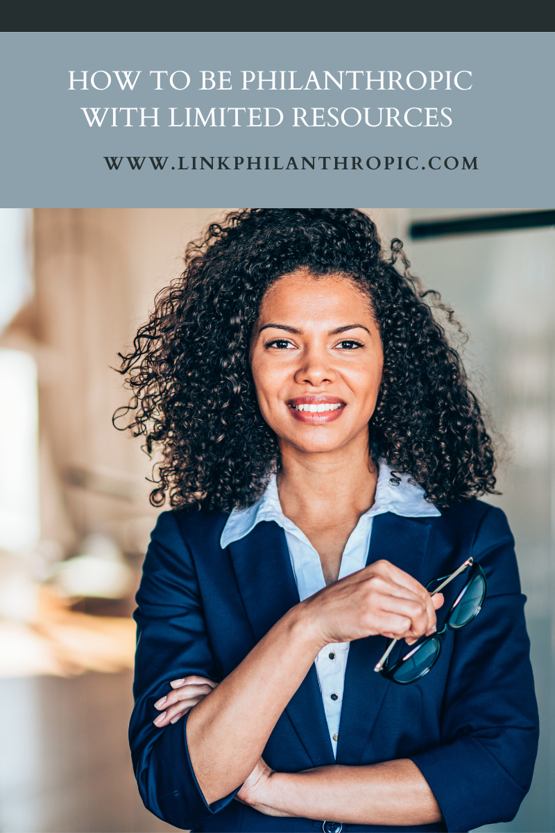 A headshot of a woman holding glasses looking into the camera with the text 'www.linkphilanthropic.com' on  the top of the image.