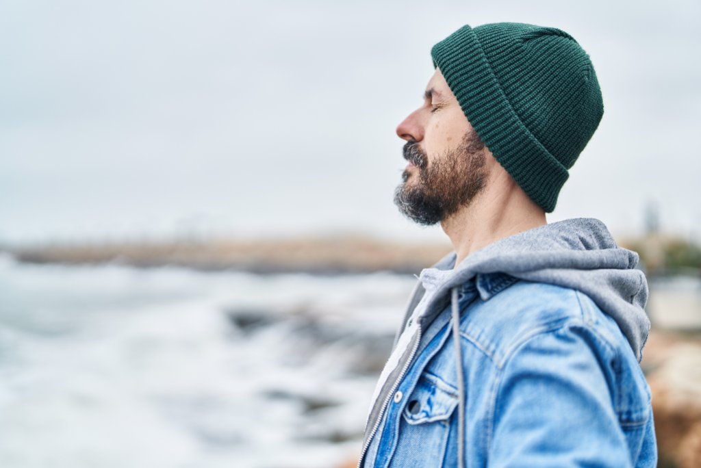 Man in peaceful contemplation by the ocean practicing breathing techniques for stress regulation during divorce