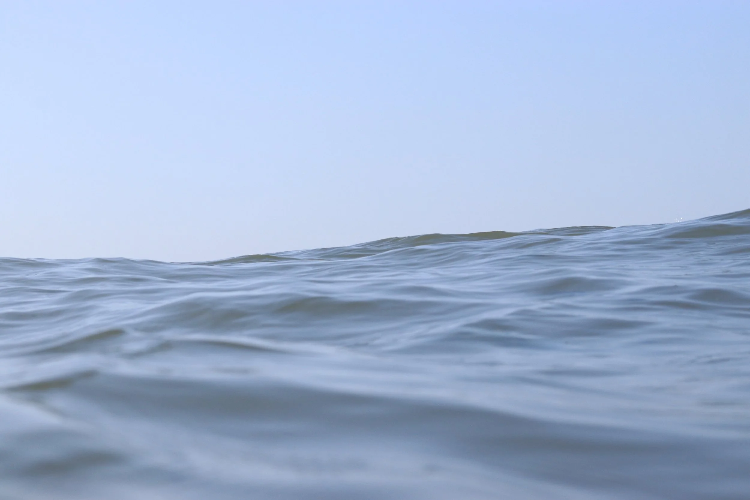 Ocean waves with a clear blue sky above.