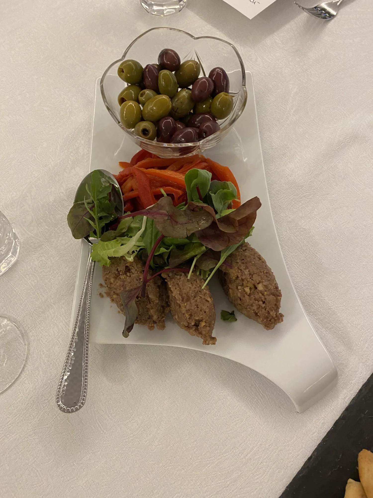 Platter of meatloaf, salad greens, carrots and olives.