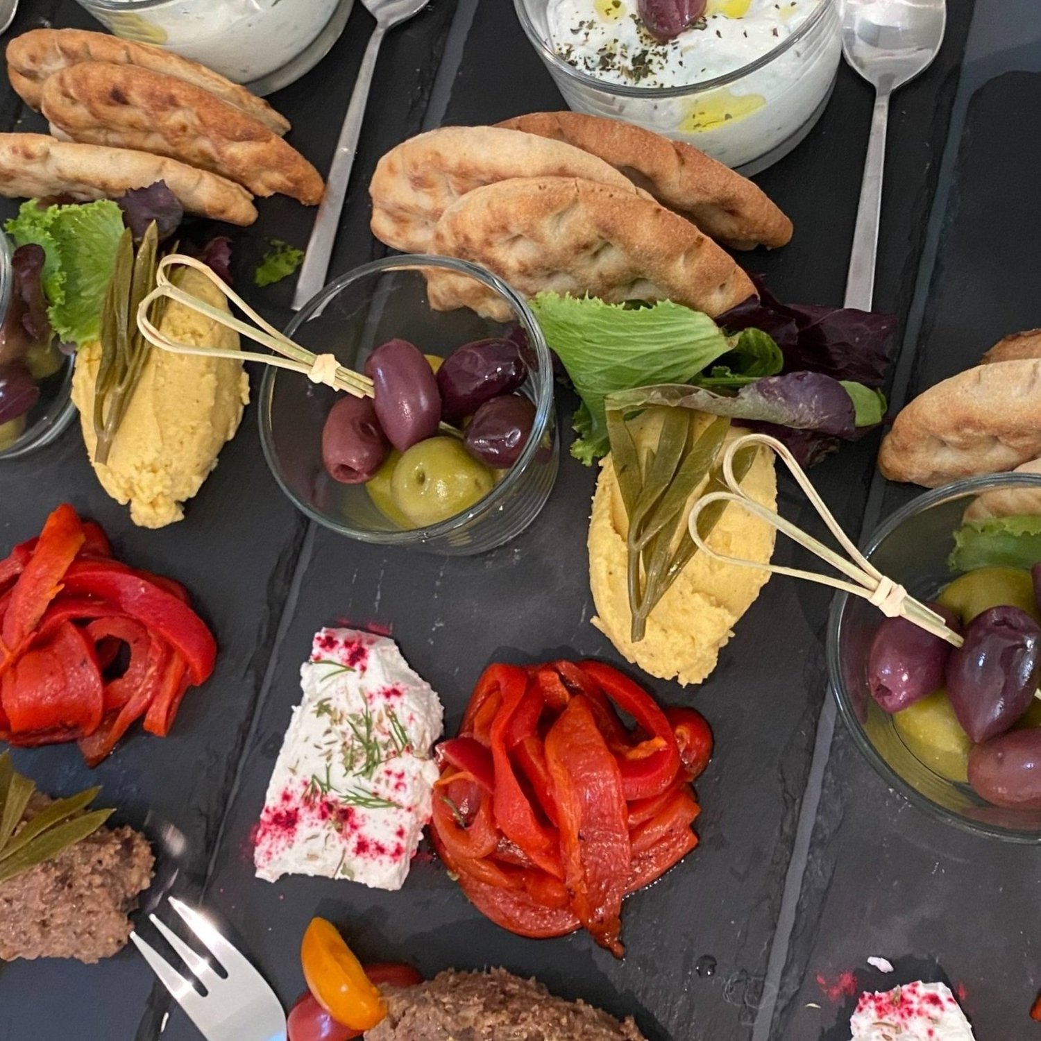 Mediterranean mezze on slate — pita, hummus, olives, peppers.