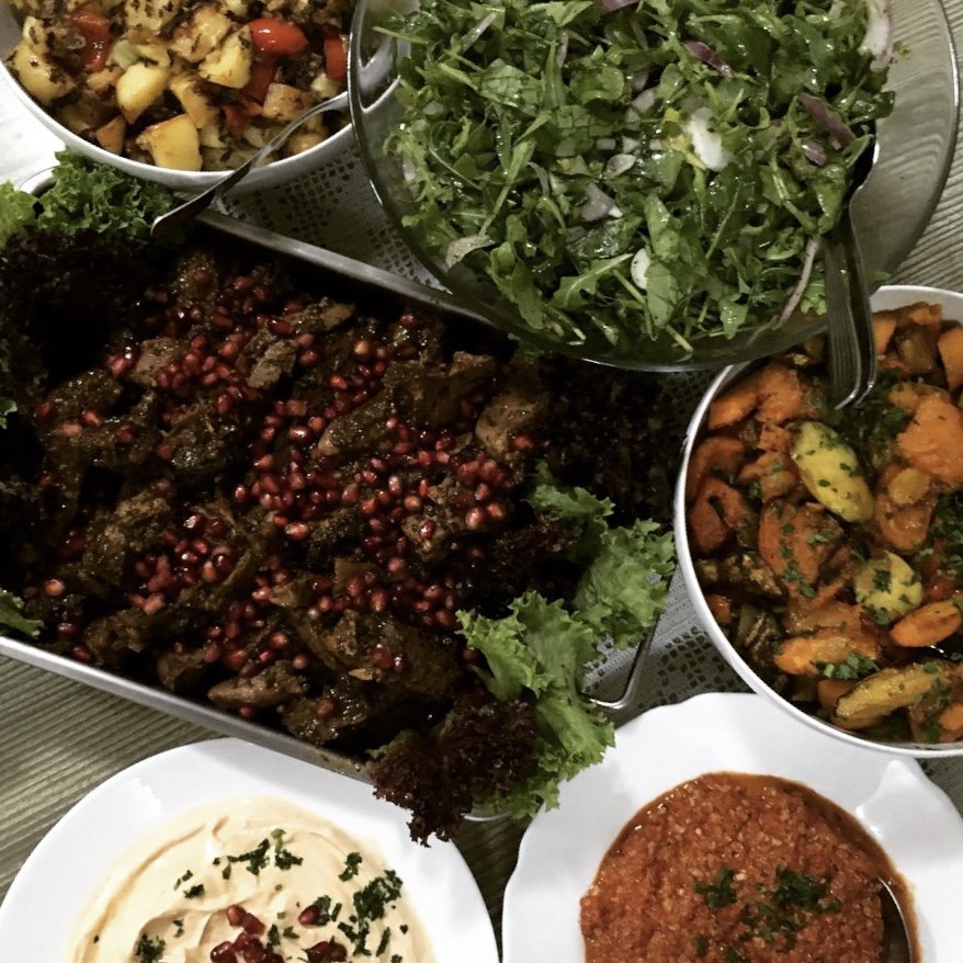 Middle Eastern feast — grilled meat, salad, hummus, sauces.