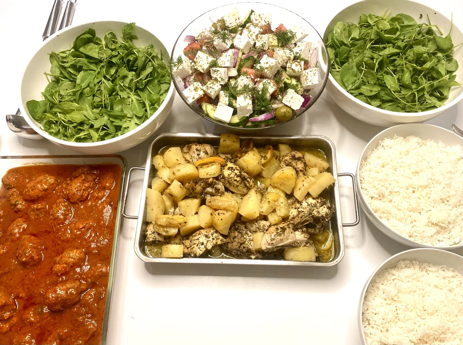 Sharing table — leafy salad, chopped salad with feta, chicken, meatballs.