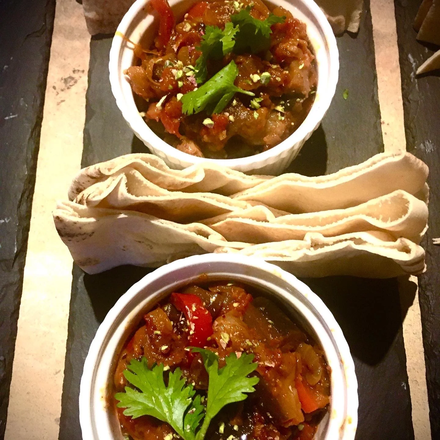 Two small bowls of Indian-style vegetable curry with cilantro.