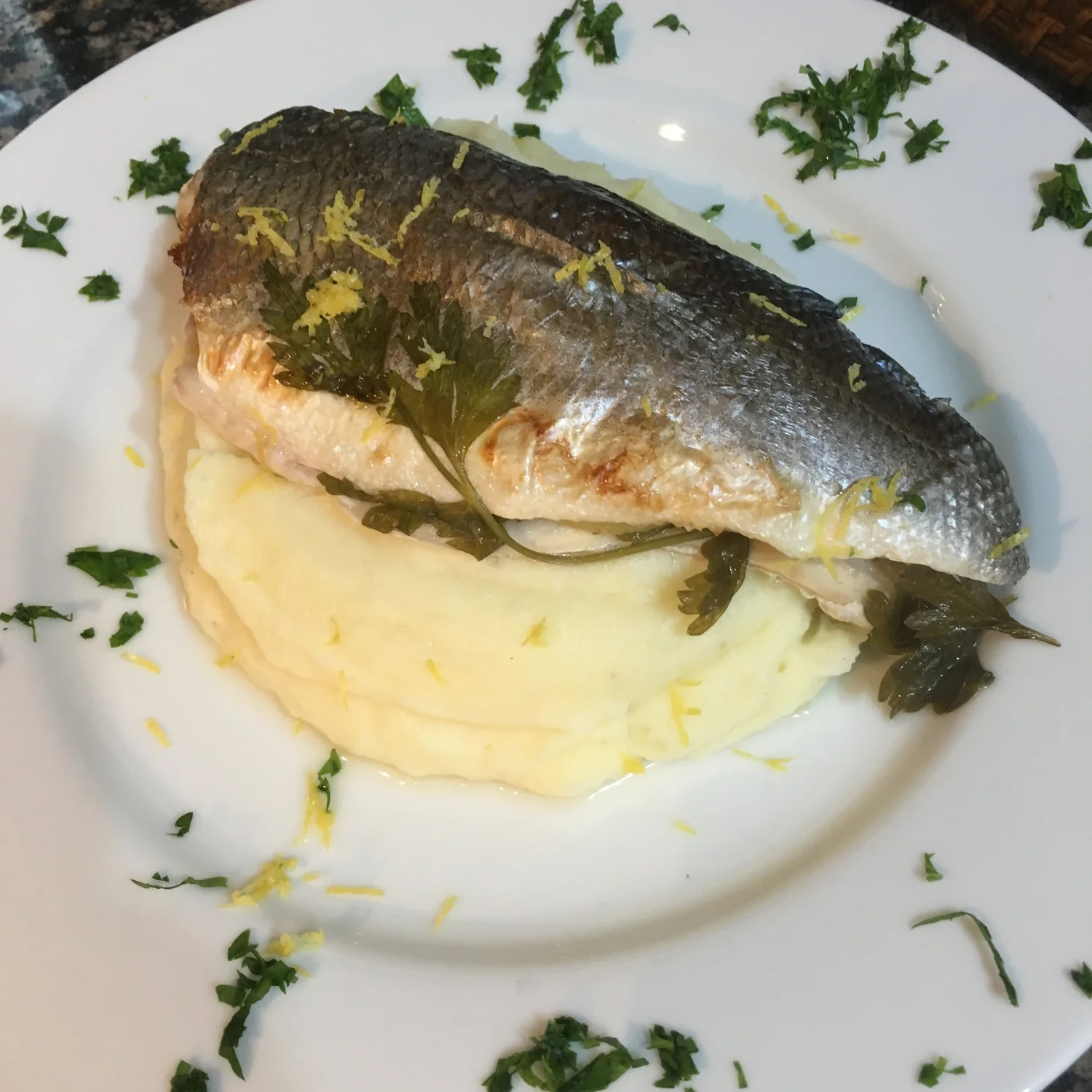 Baked fish fillet with parsley on mashed potato.