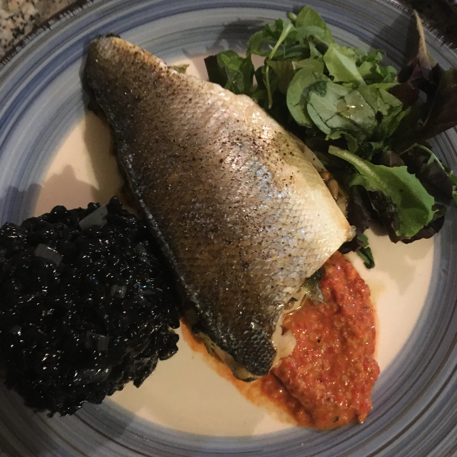 Crispy-skinned fish fillet with black rice and tomato salsa.