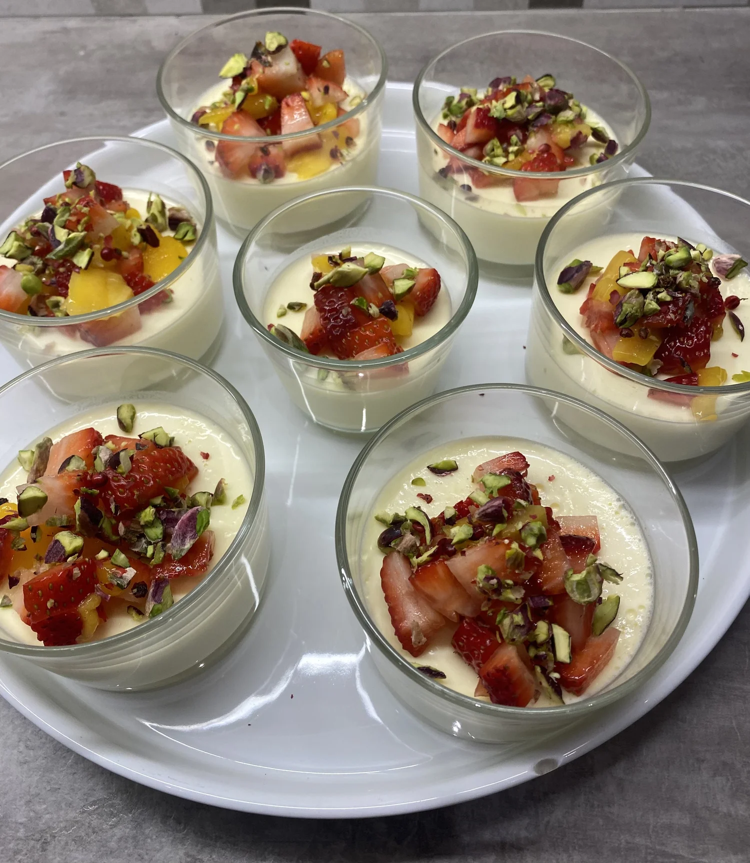 Dessert cups of cream, strawberry, peach and pistachio.