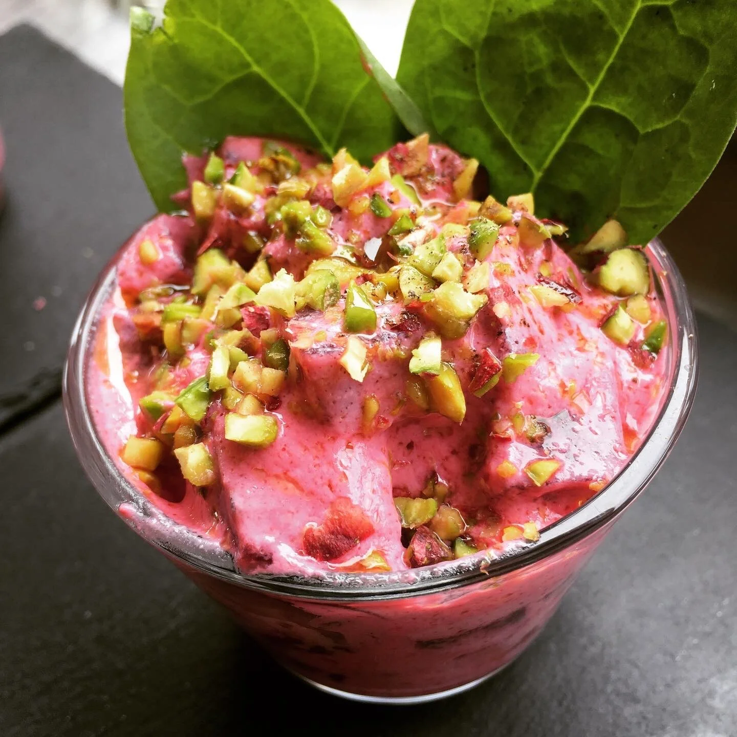 Pink creamy dessert topped with pistachios.