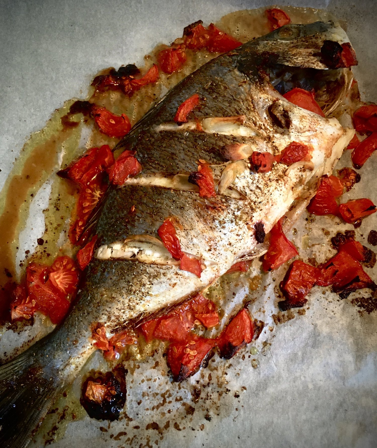 Whole sea bream with roasted cherry tomatoes and garlic.