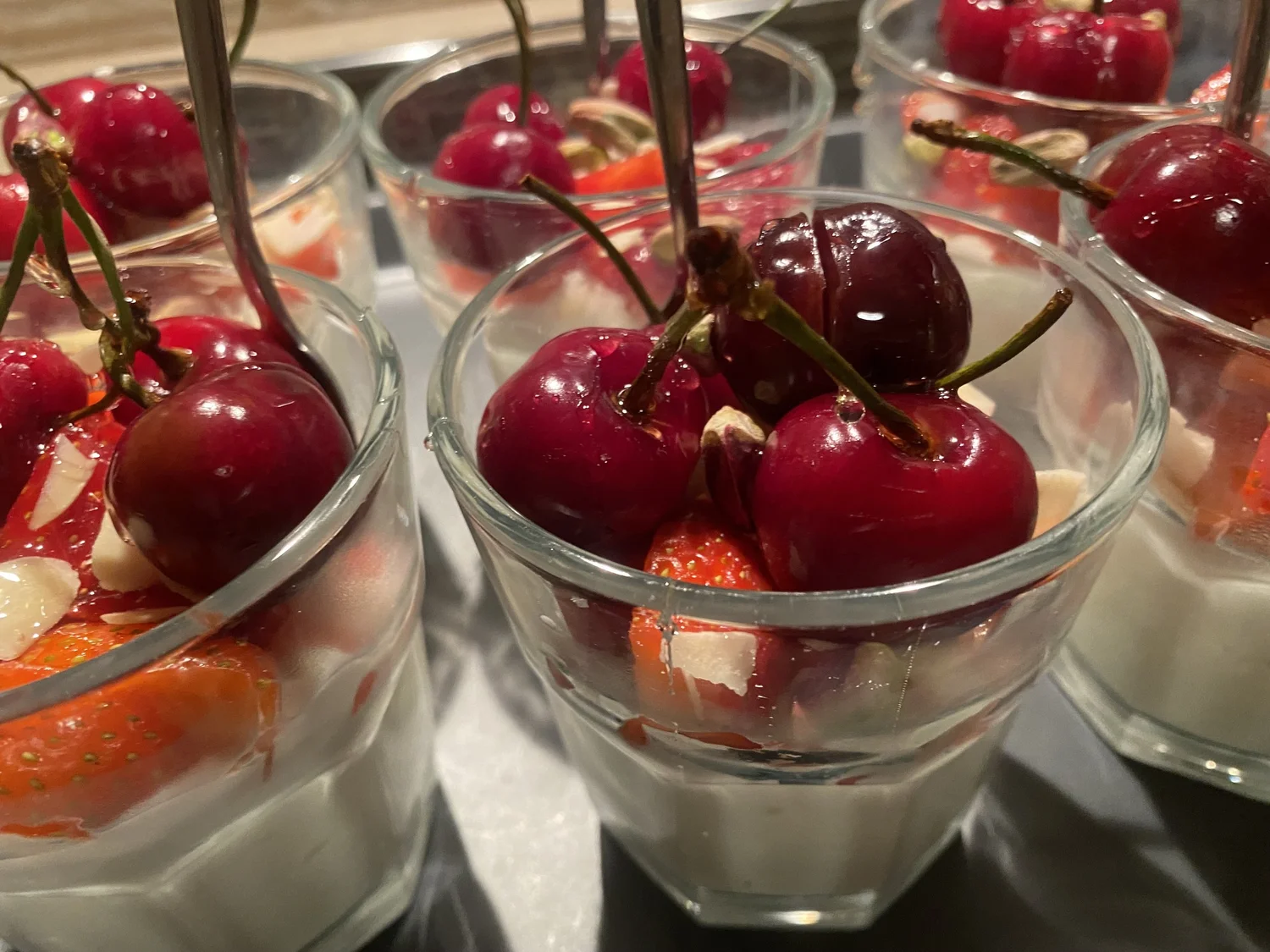 Glass cups of cream with strawberries, cherries and almonds.