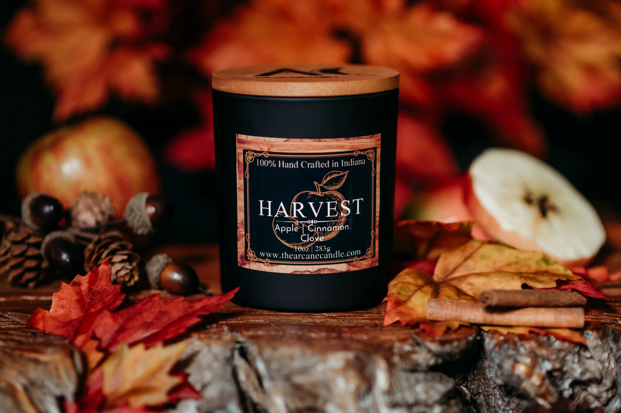 HARVEST apple pie scented candle with baked apple, cinnamon and clove surrounded by autumn leaves and cinnamon sticks.