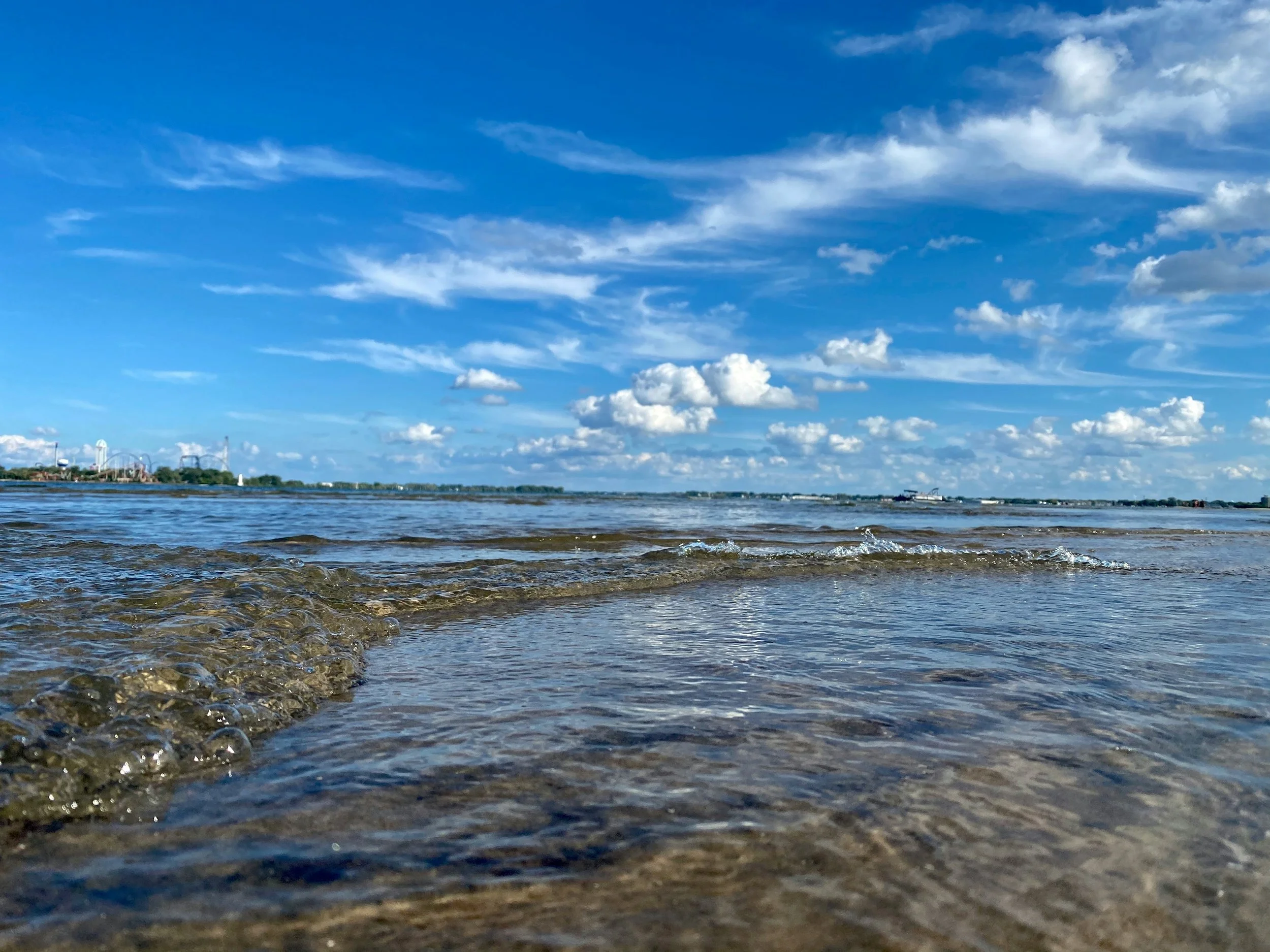 gentle waves on a clear blue lake on a sunny day with the skyline of sandusky, ohio in the background