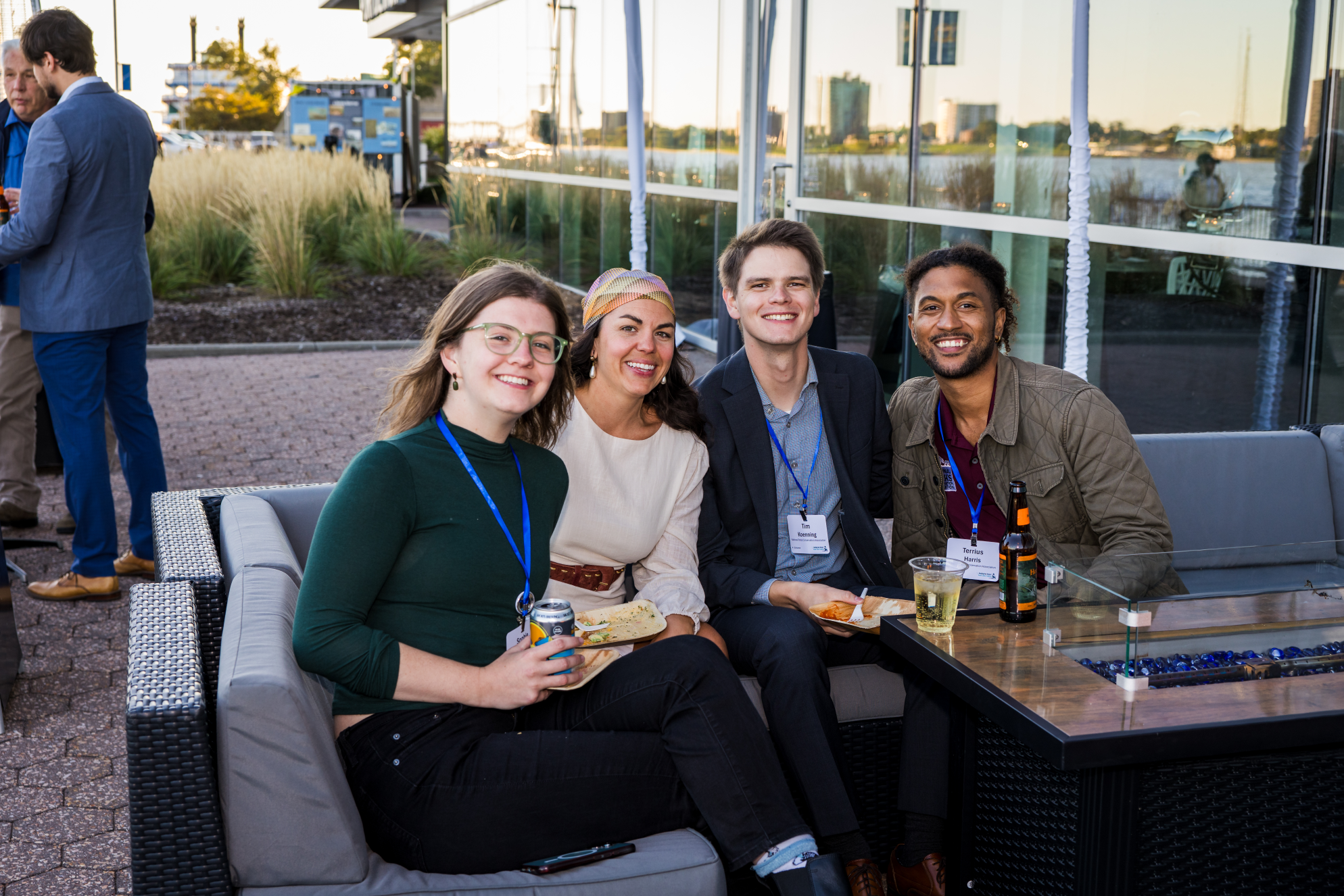 Four smiling young people sit outside on a couch.