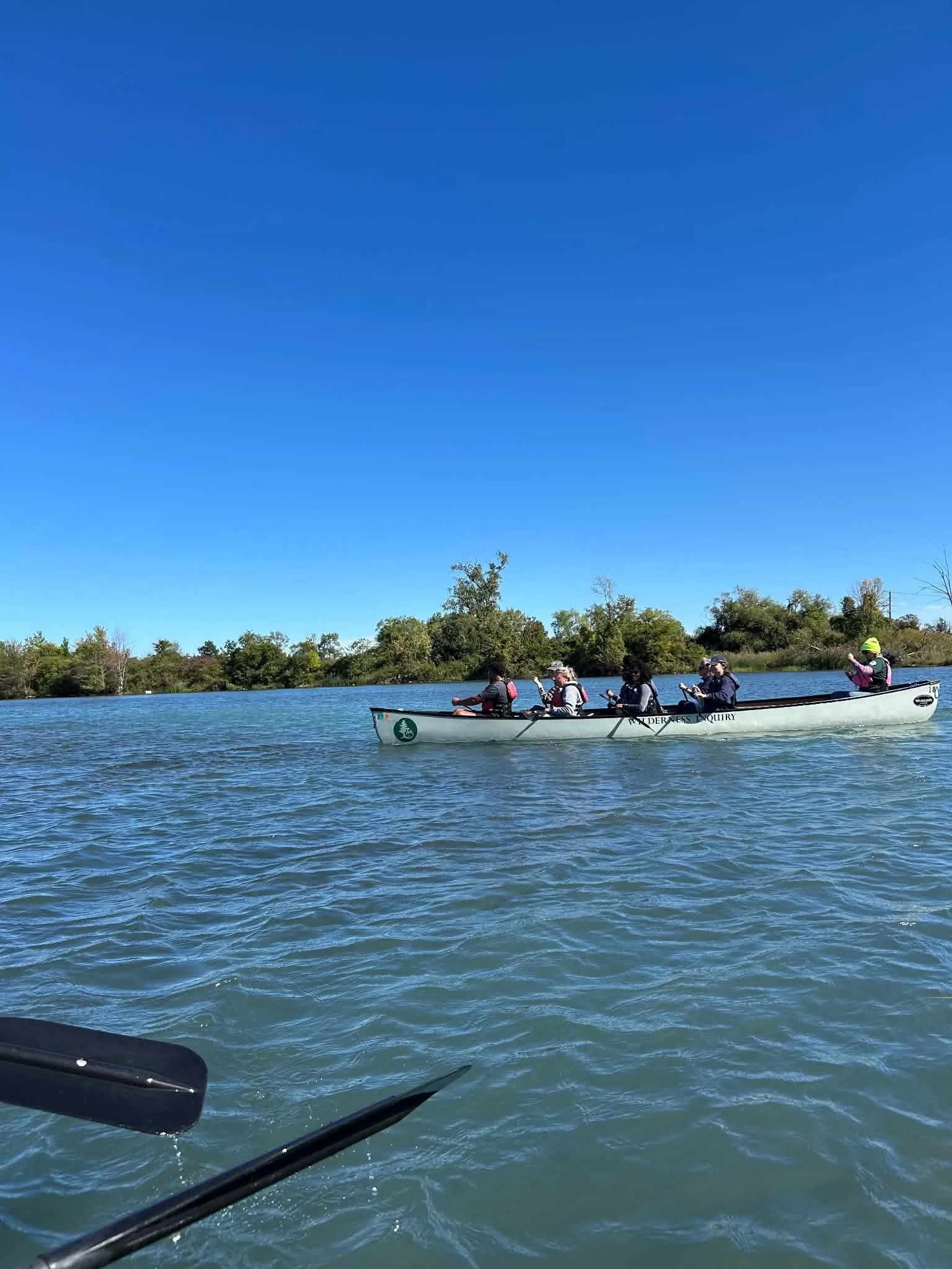 A small group of people in a canoe paddle on the water on a sunny day.