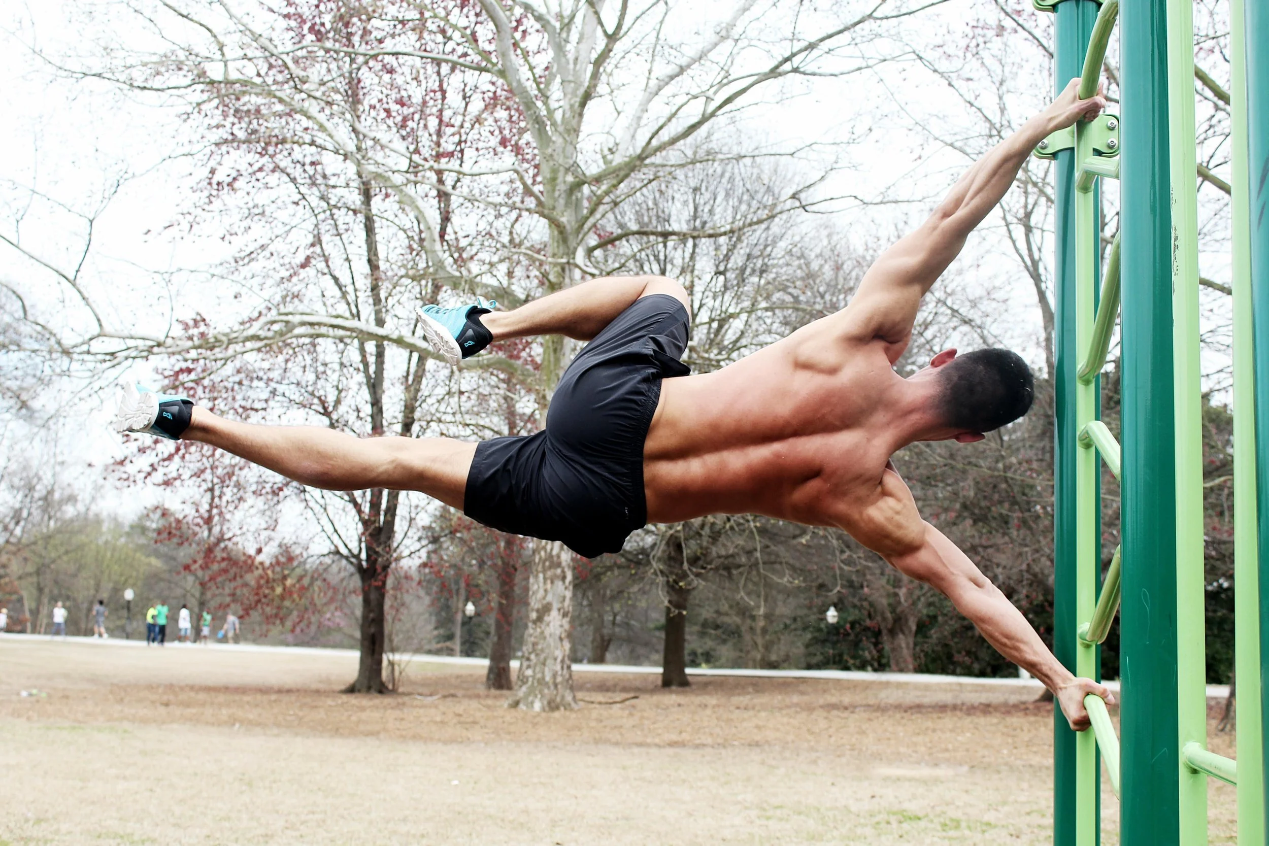Man performing human flag exercise on outdoor gym equipment