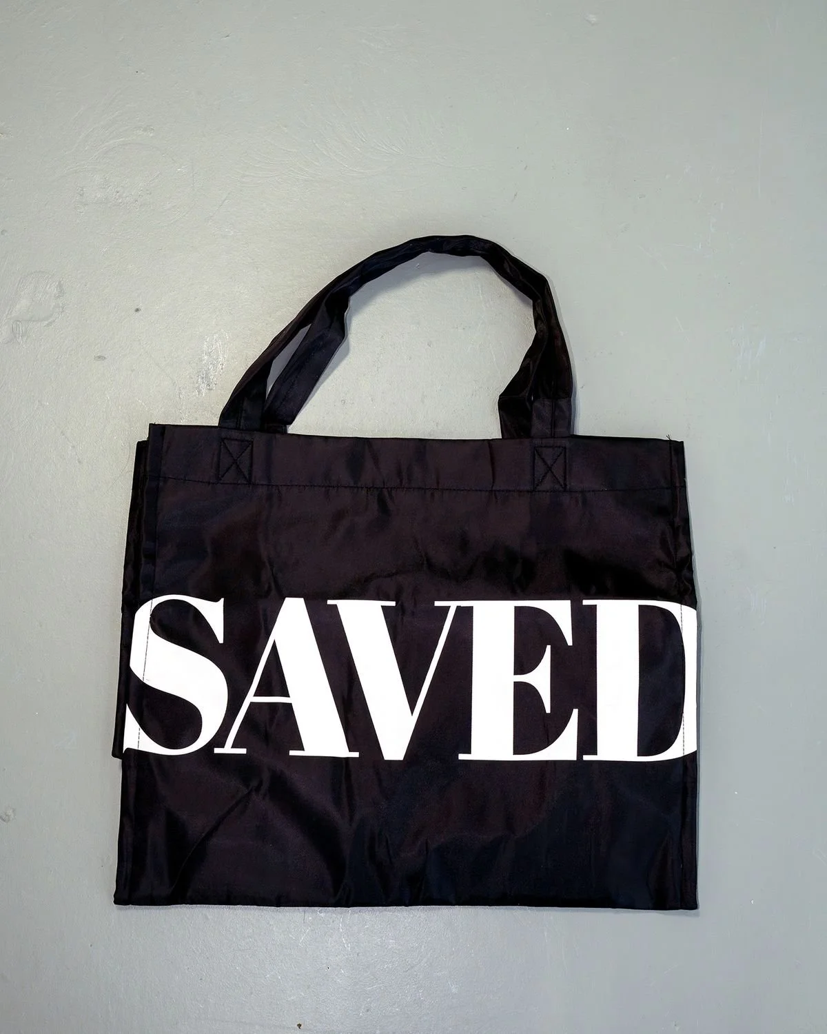 Black SAVED tote bag laid flat