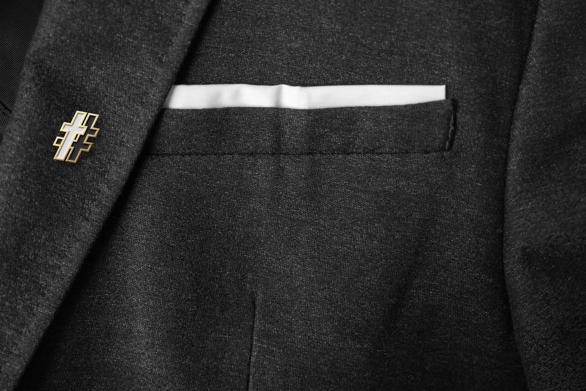 Gold and enamel # cross lapel pin on a charcoal blazer