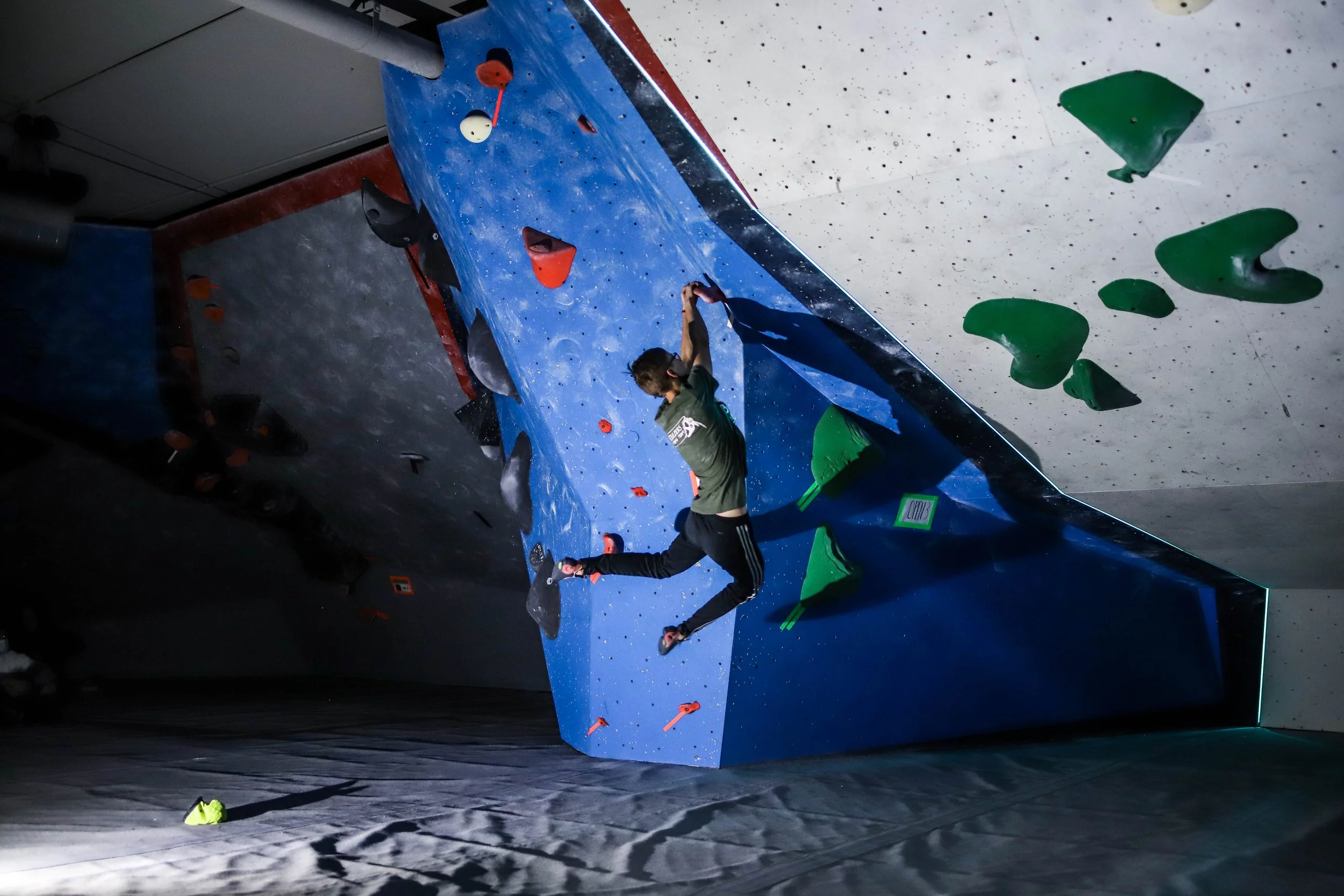 Person rock climbing indoors on a wall with colorful holds