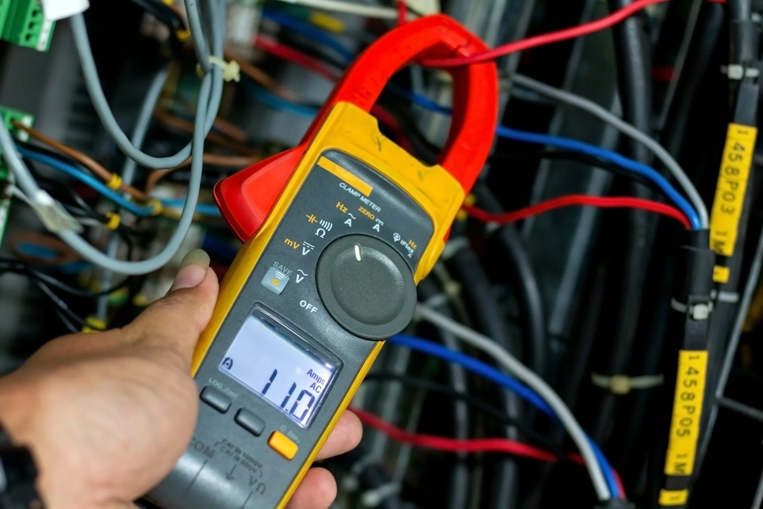 Technician measuring inverter current with a clamp meter