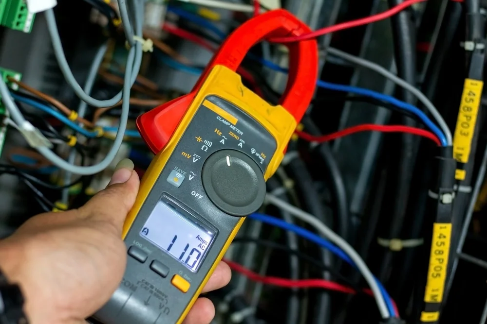 Technician measuring inverter current with a clamp meter