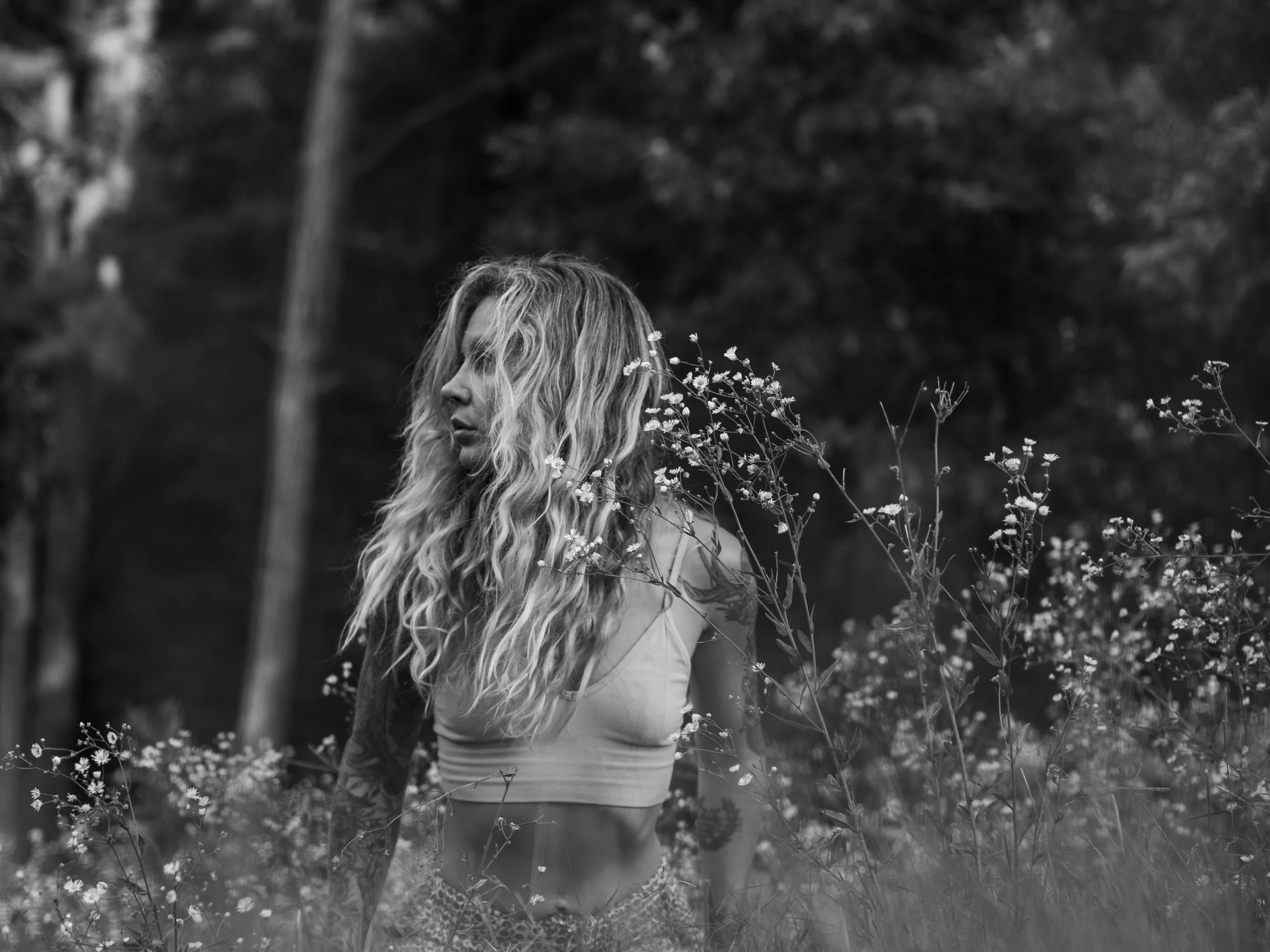 Sierra La Rue Redfield standing among tall wildflowers at the edge of a forest.