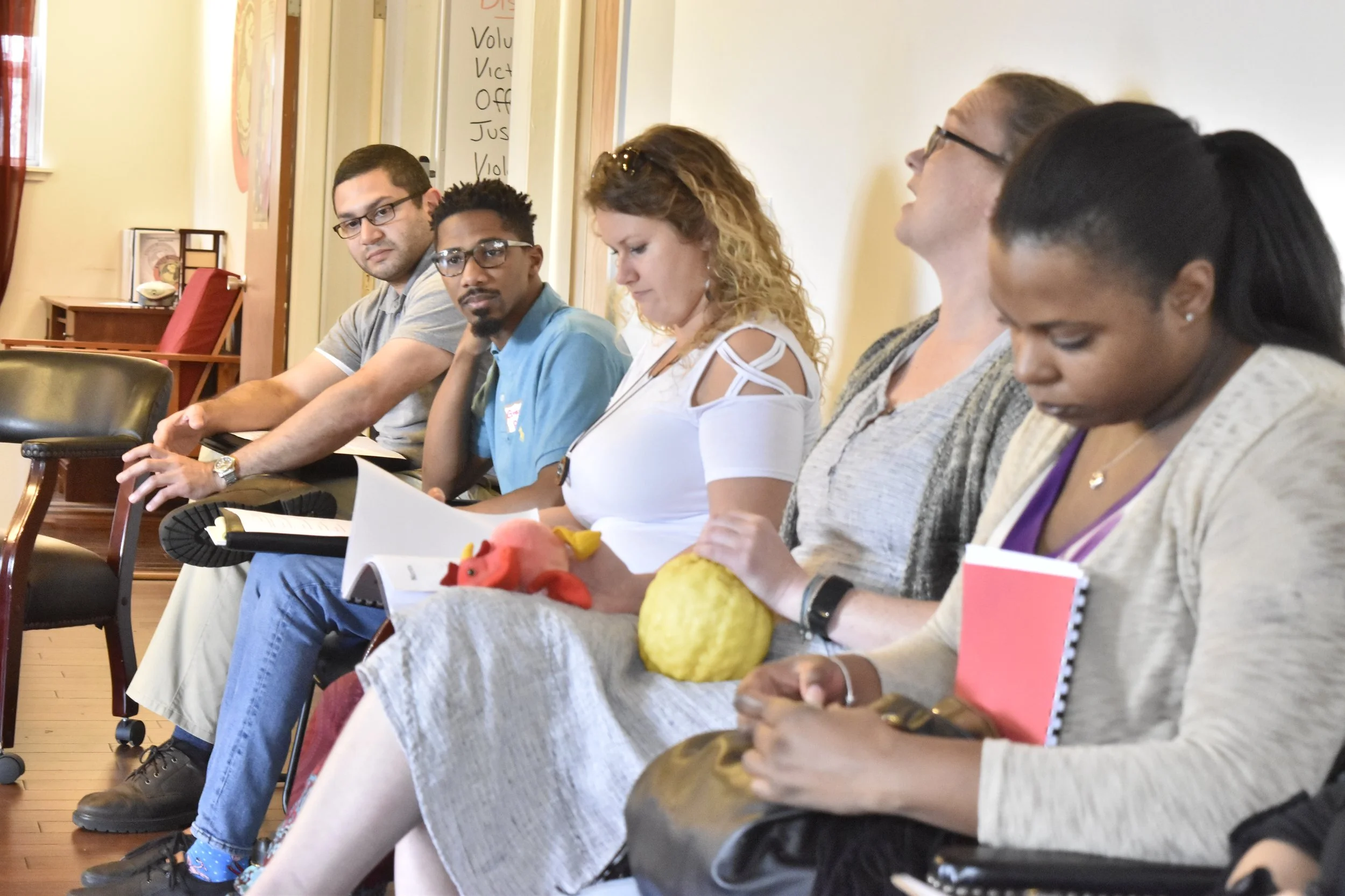 Workshop participants seated in circle taking notes during peacebuilding session