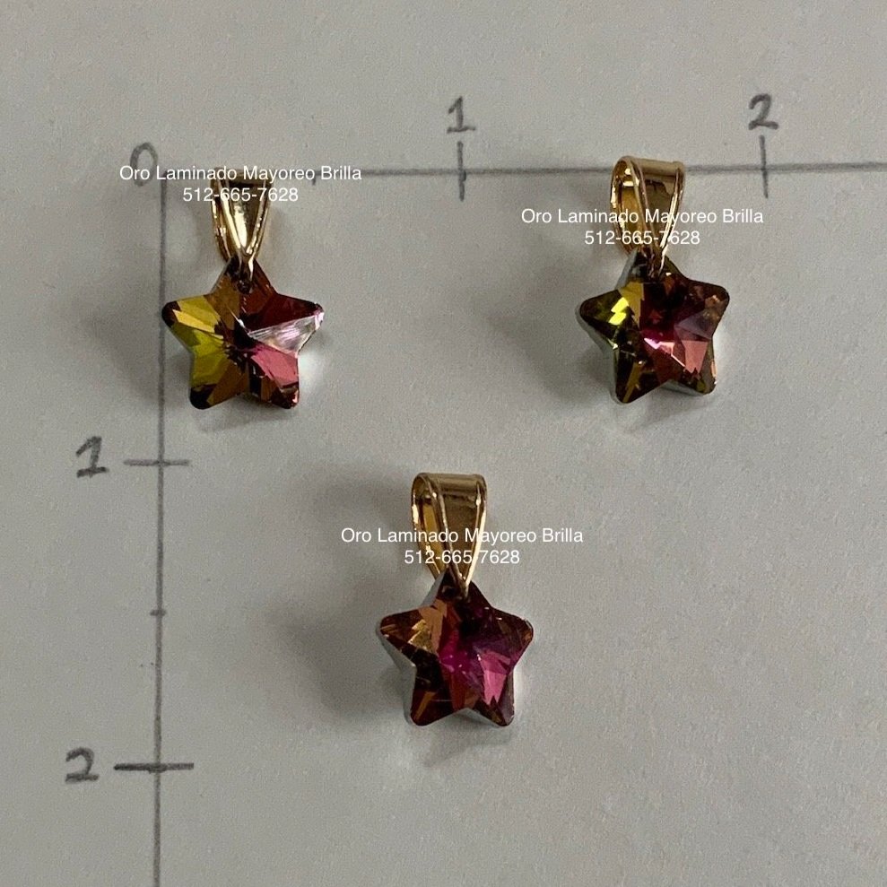 "Paquete de 3 dijes de oro laminado en forma de estrella con cristales tornasol multicolor." "3-pack of laminated gold star-shaped charms with multicolor iridescent crystals."