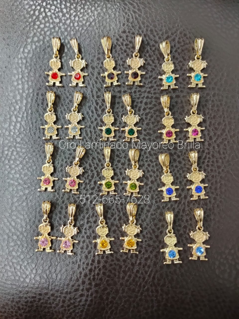 "Paquete de 24 dijes de oro laminado con figuras de niños y niñas decorados con piedras de colores." "24-pack of laminated gold charms with boy and girl figures adorned with colorful stones."