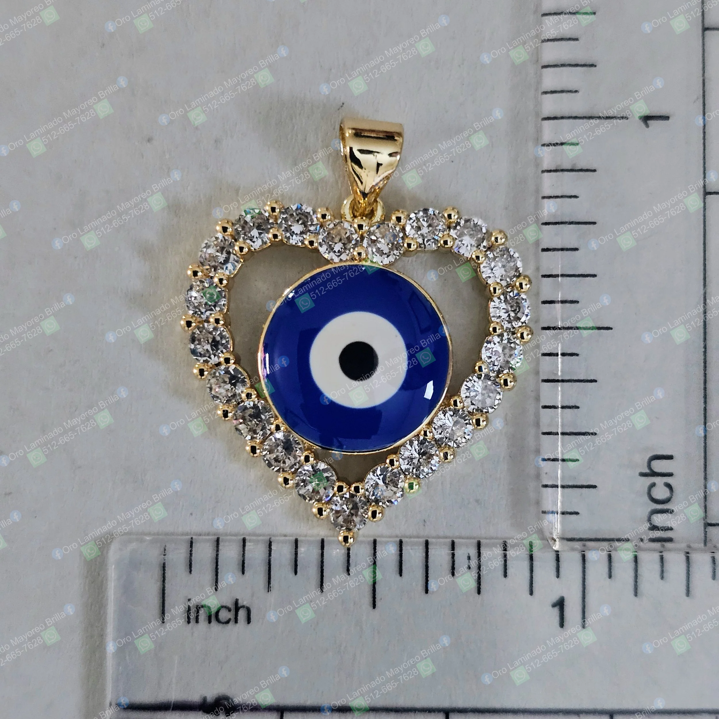 Dije de corazon color oro con ojo turco azul y piedras decorativas visibles | Gold color heart pendant with blue eye of protection and visible decorative stones