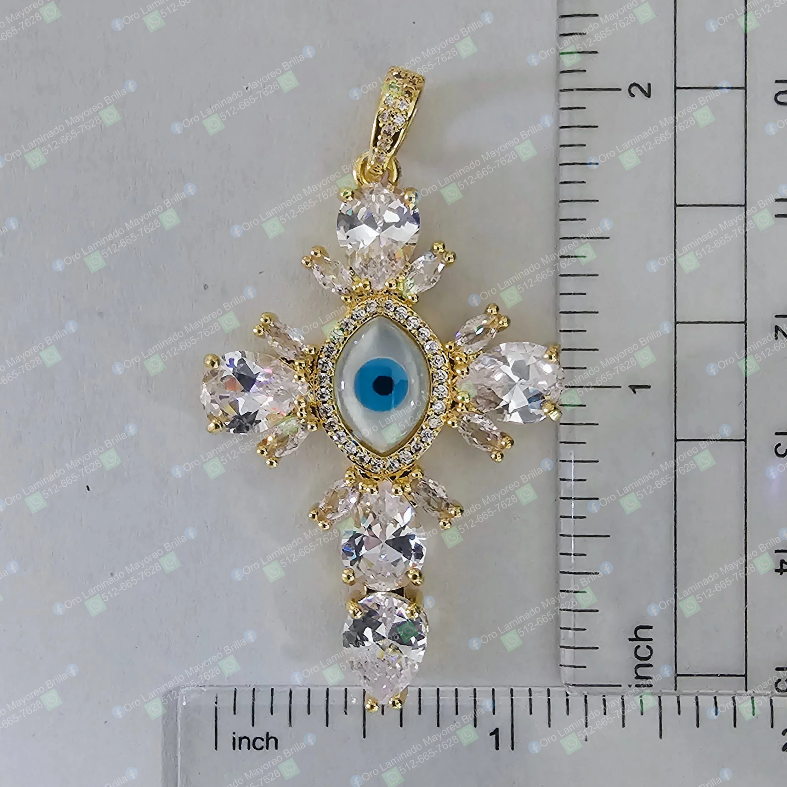 Dije cruz color oro con ojo turco y piedras decorativas visibles | Gold color cross pendant with eye of protection and visible decorative stones