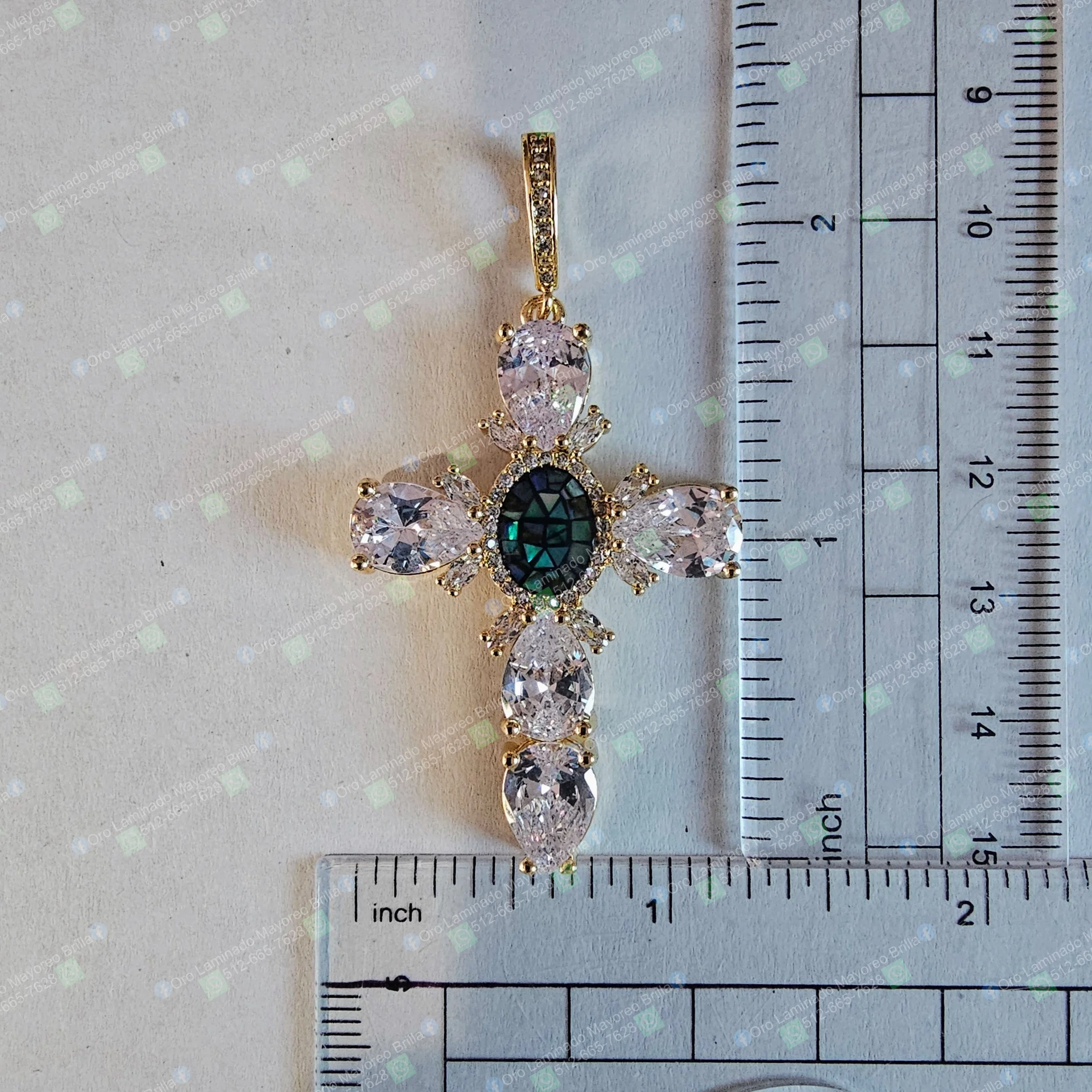 Dije cruz color oro con piedras decorativas visibles y piedra central ovalada oscura | Gold color cross pendant with visible decorative stones and dark oval central stone