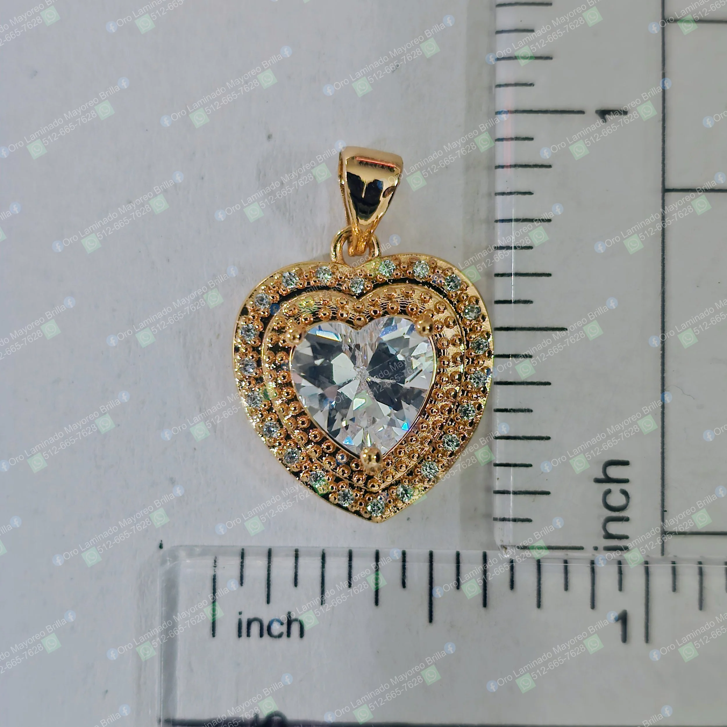 Dije de corazon color oro con piedras decorativas visibles y piedra central brillante | Gold color heart pendant with visible decorative stones and brilliant centerpiece stone