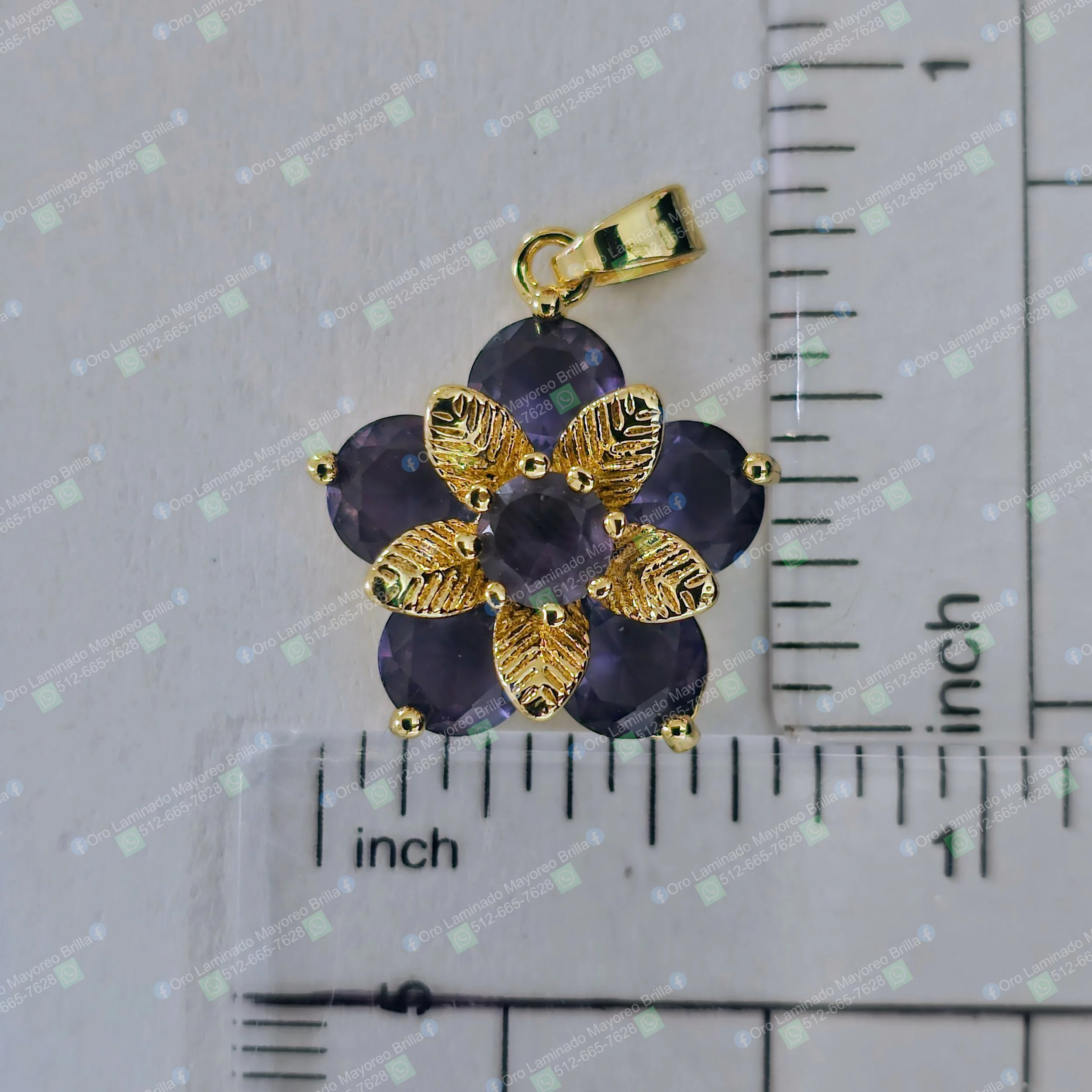 Dije flor color oro con hojas texturizadas y piedras decorativas moradas visibles | Gold color flower pendant with textured leaves and visible purple decorative stones